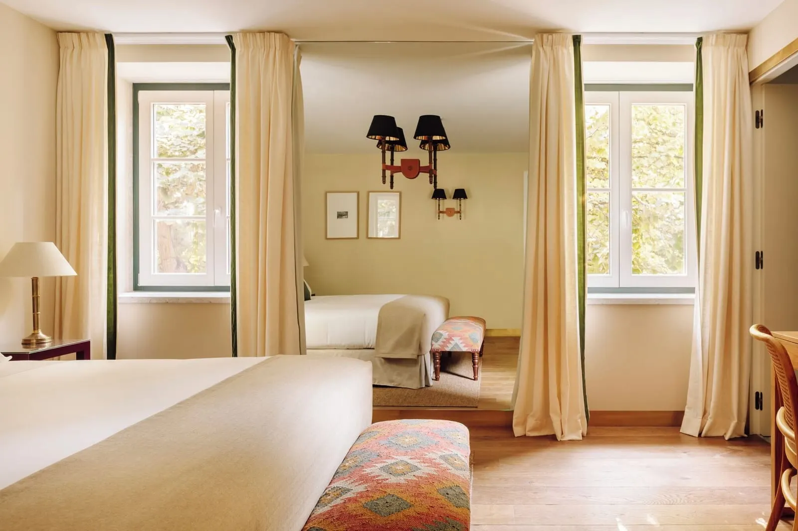 Deluxe Garden View room at Hotel das Amoreiras: two curtained windows looking onto trees, seen from the foot of the bed