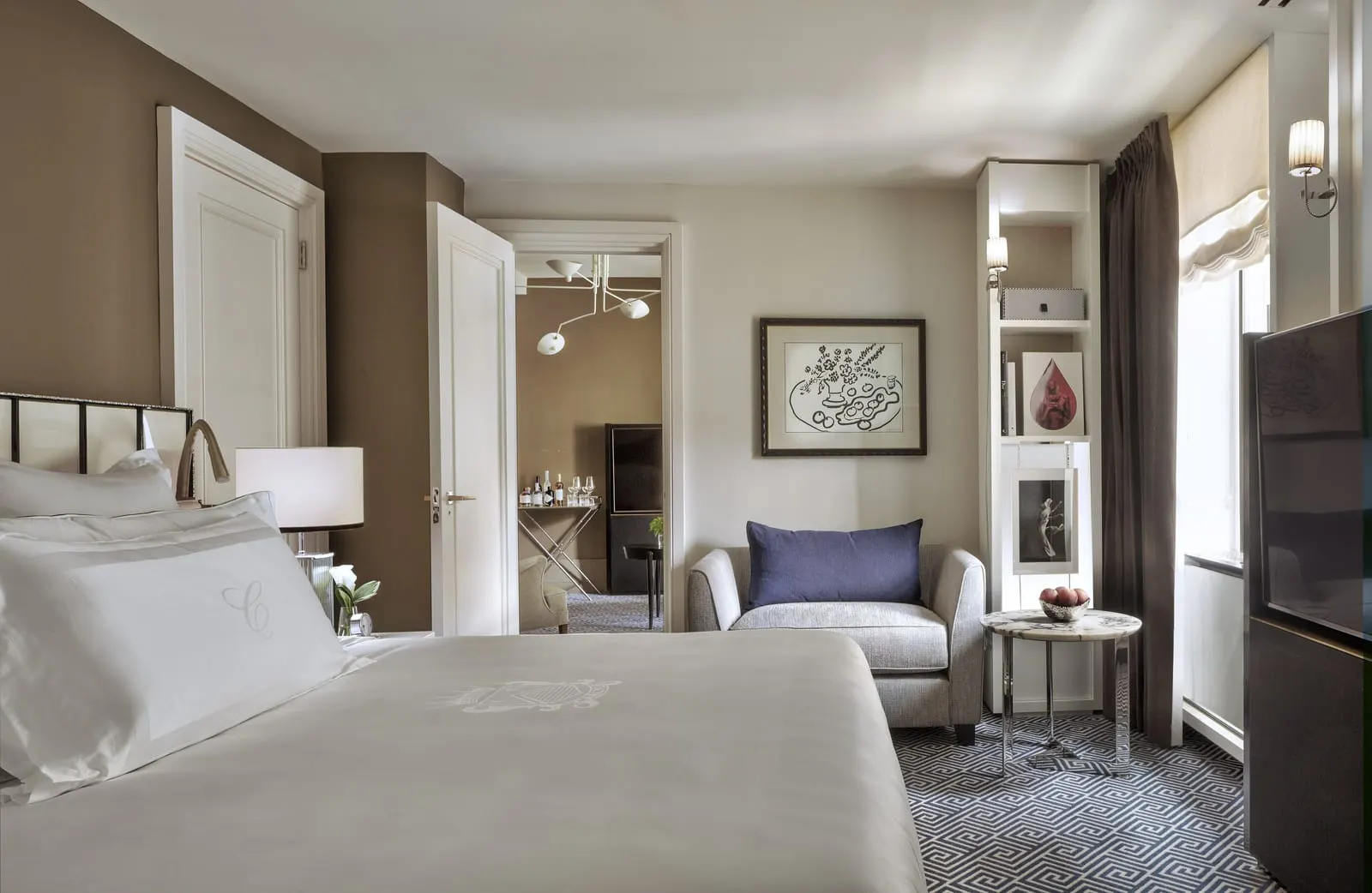 Executive King at The Carlyle: a king bed with an armchair by the window, and an open door through to a separate lounge