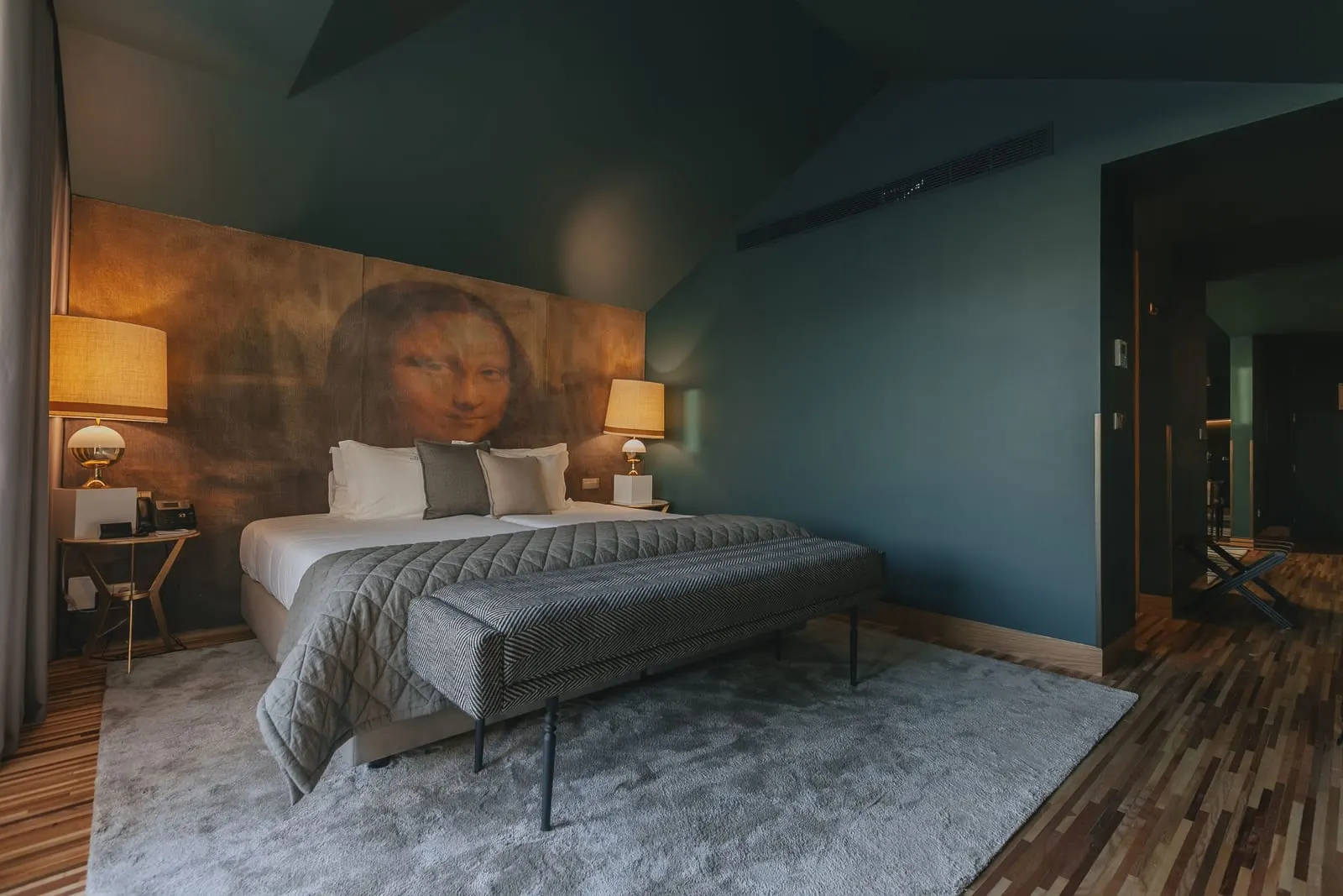 Royal Jacuzzi Suite at Torel Avantgarde: the bed below a large Mona Lisa mural, with a bench at its foot