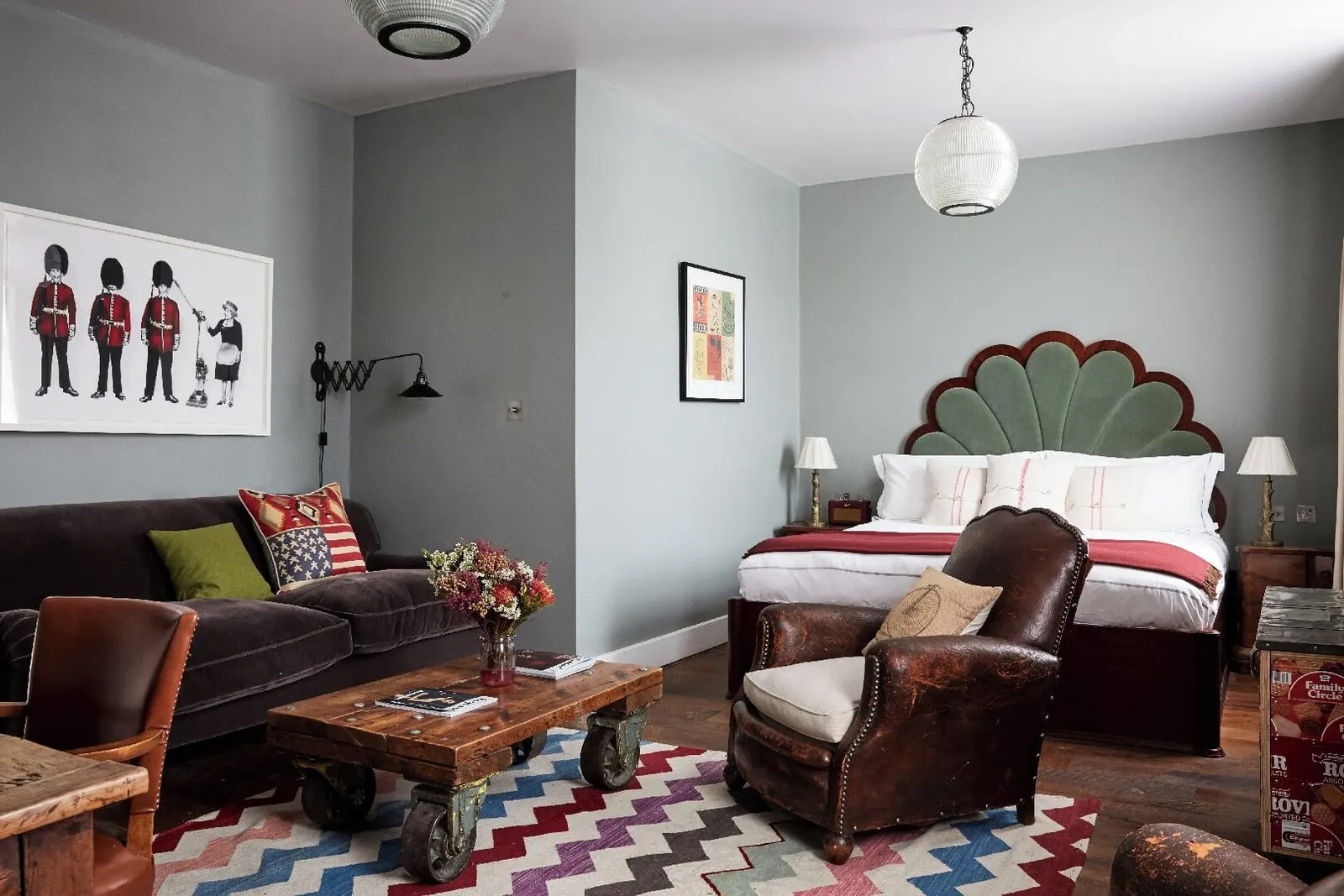 Club Suite at Artist Residence London: a velvet sofa, leather armchairs, a zigzag rug and the bed with a scalloped headboard