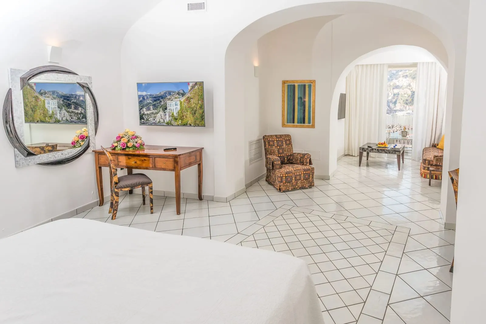 Suite（Hotel Marina Riviera）：手前にベッドがあるワンルームに、ライティングデスクと、アーチの先のアームチェアのあるくつろぎのコーナー