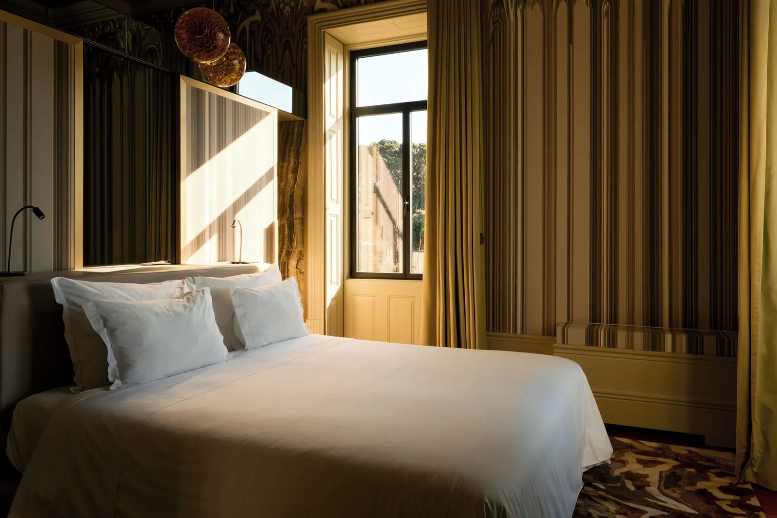 Vila Foz Suite at Vila Foz Hotel: the bed, striped wallpaper and a tall window with gold curtains