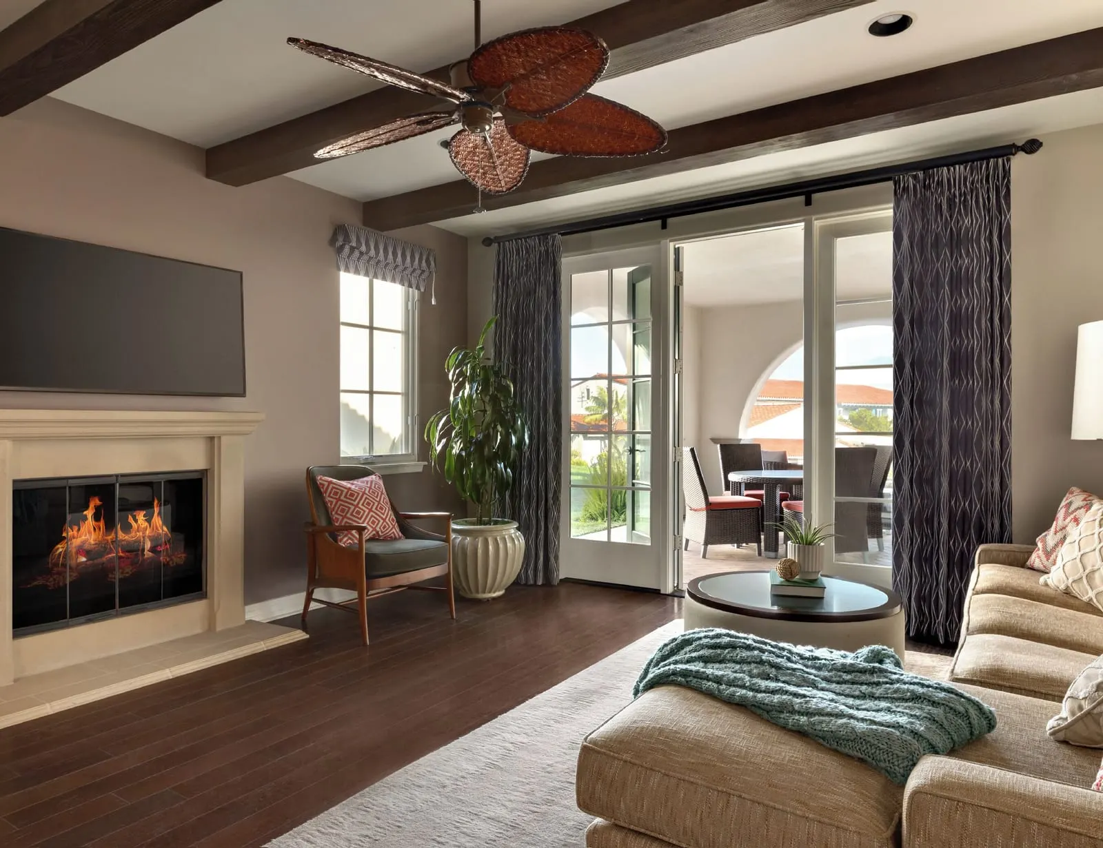 Two-Bedroom Bungalow at Terranea Resort: a living room with a fireplace, a wall-mounted television, a sofa and glass doors onto a covered patio, under a beamed ceiling
