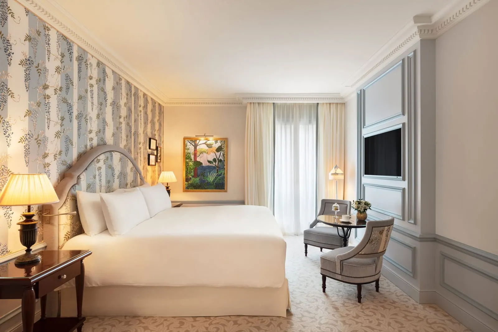 Prestige Room at Hôtel Métropole Monte-Carlo: the bed against blue floral wallpaper, with two armchairs by the window