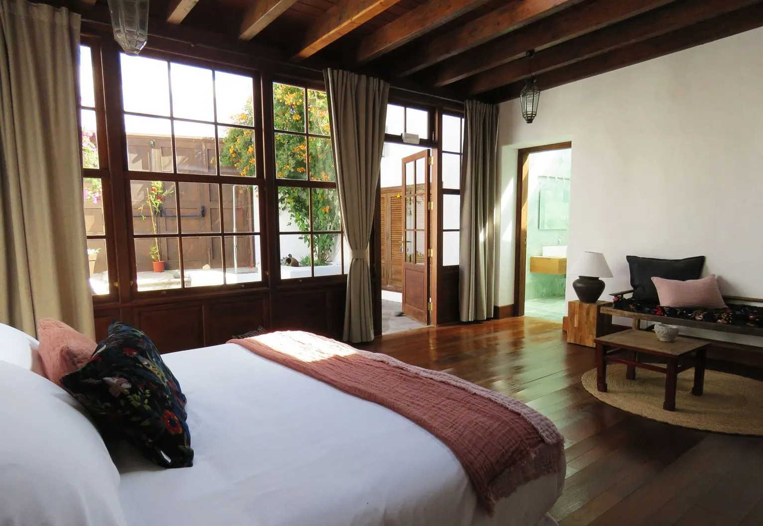 Suite 04 at Hotel Boutique Palacio Ico: a bed and a sitting area beside tall wood-framed windows under a beamed ceiling