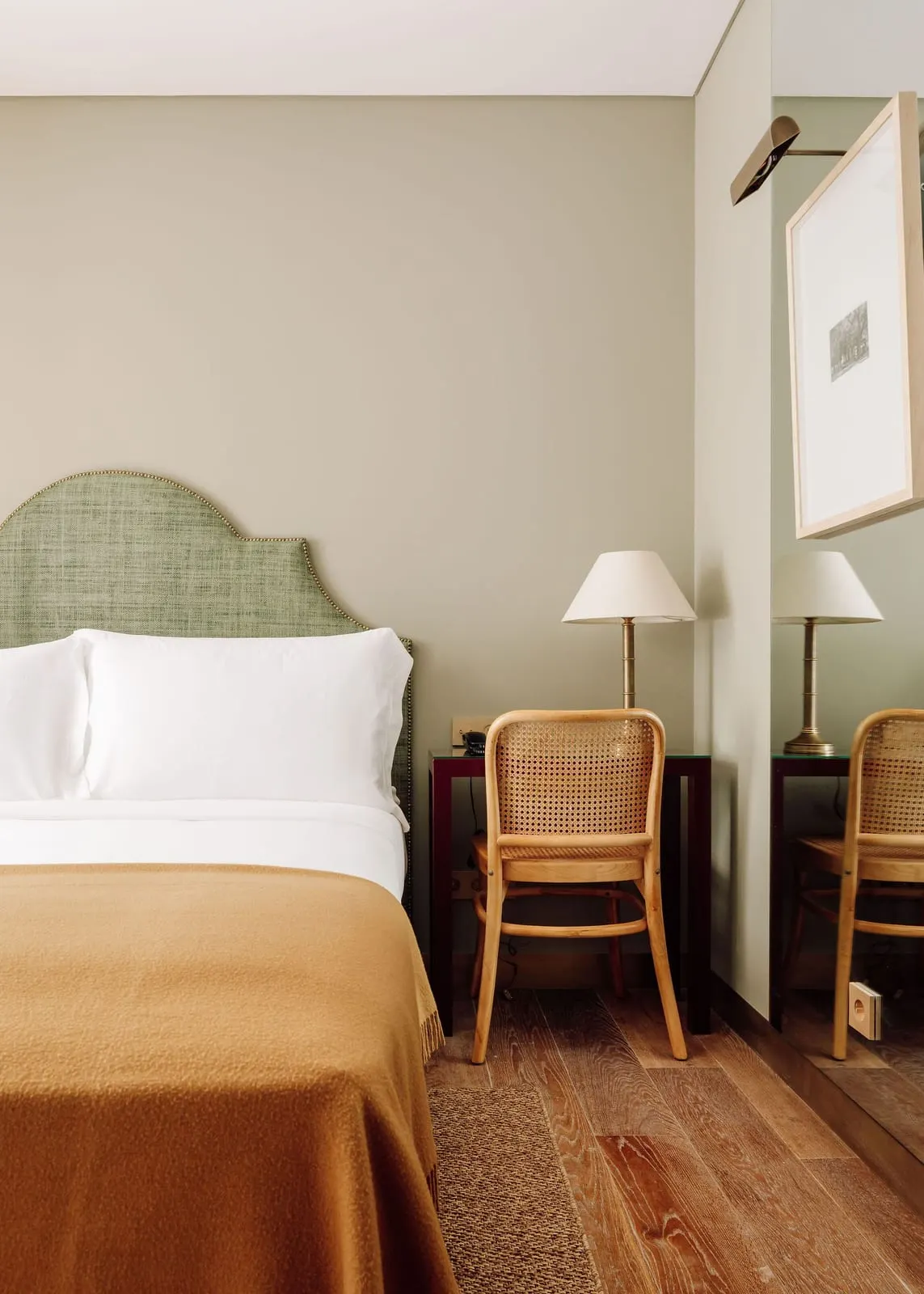Mini Deluxe room at Hotel das Amoreiras: the bed with a green headboard, and a lamp and cane chair at a small desk