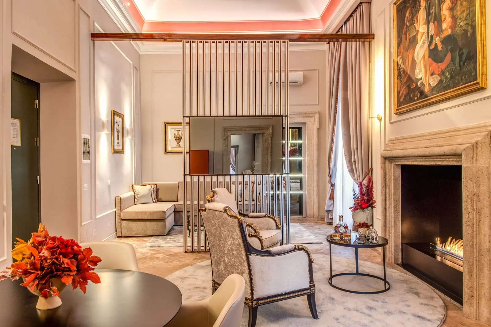 Suite Luxury with view at Eitch Borromini Palazzo Pamphilj: the sitting room with a lit fireplace, a large painting and a slatted screen