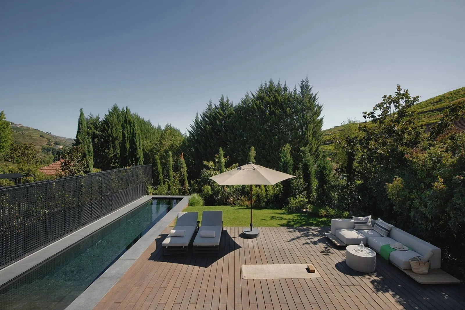 One Bedroom Pool Villa at Six Senses Douro Valley: a long pool beside a wooden deck with loungers, a parasol and a sofa