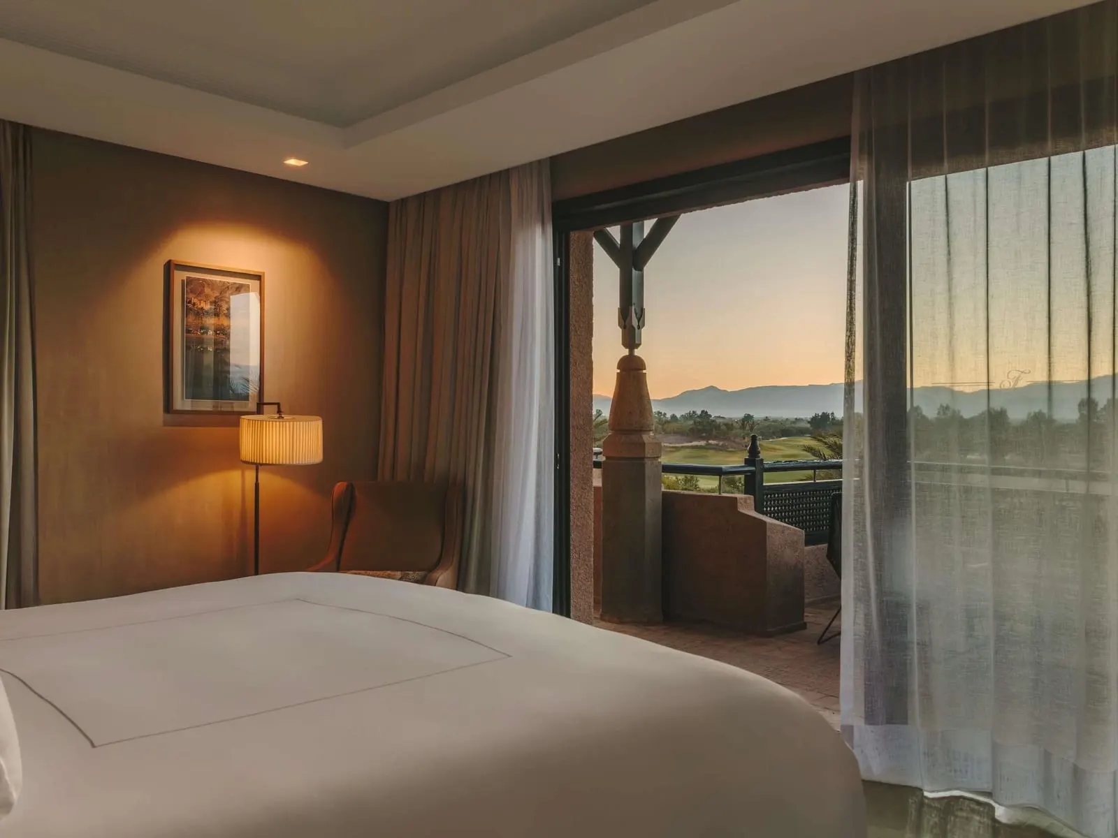 Presidential Suite im Fairmont Royal Palm Marrakech: ein Schlafzimmer mit hohen Fenstern und Vorhängen in der Abenddämmerung