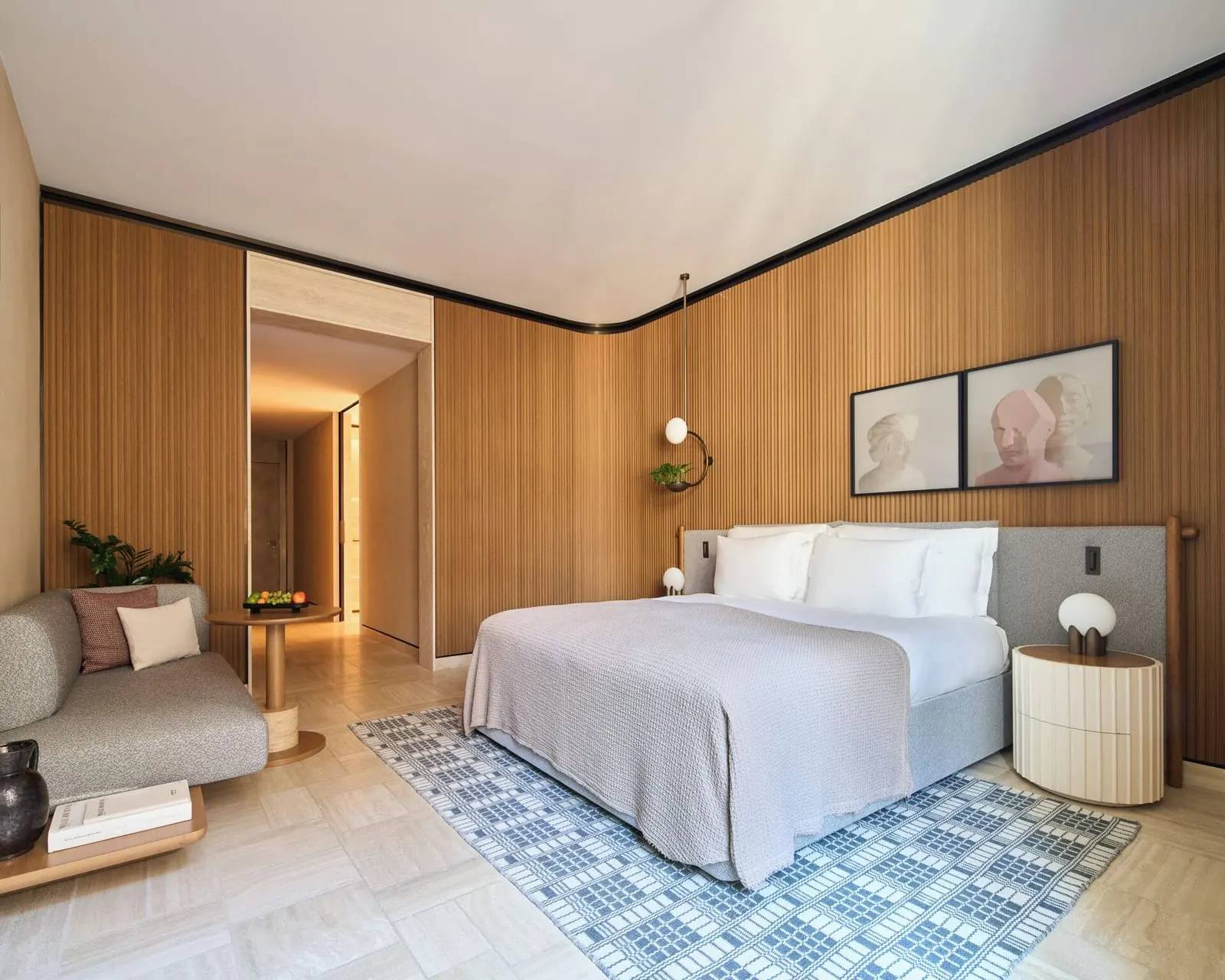 Junior Suite at Six Senses Rome: the bed, a grey sofa and a patterned rug under slatted wood walls