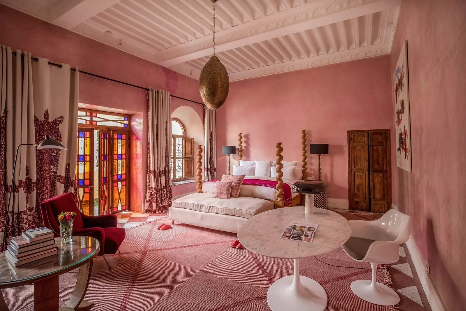 Extra Large Room at El Fenn: a pink room with a bed, a round marble table with chairs and stained-glass doors