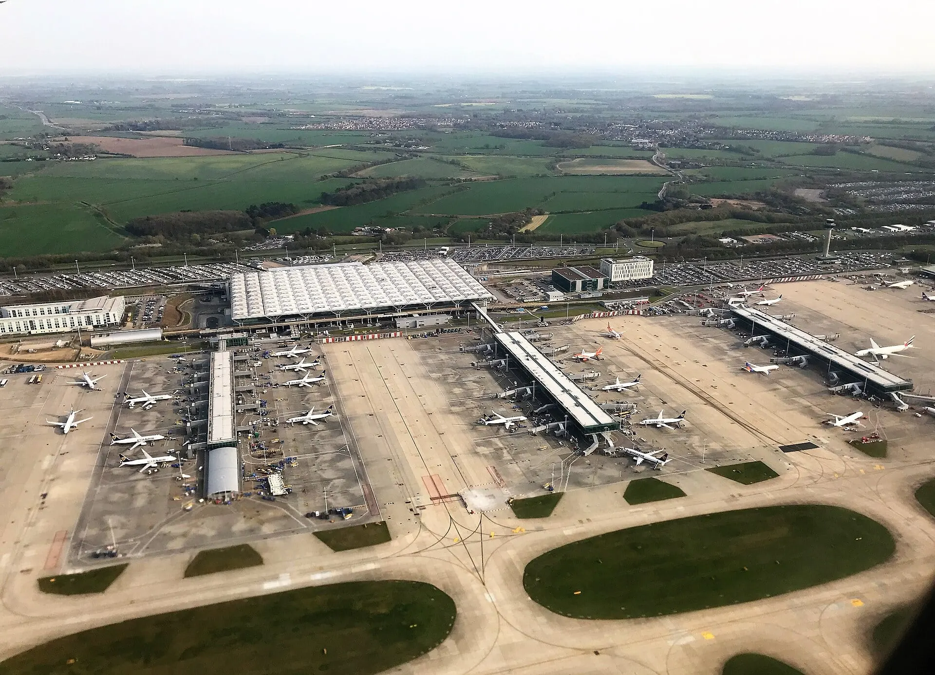 Stansted Airport from the air, with the terminal, satellites and aircraft at the gates