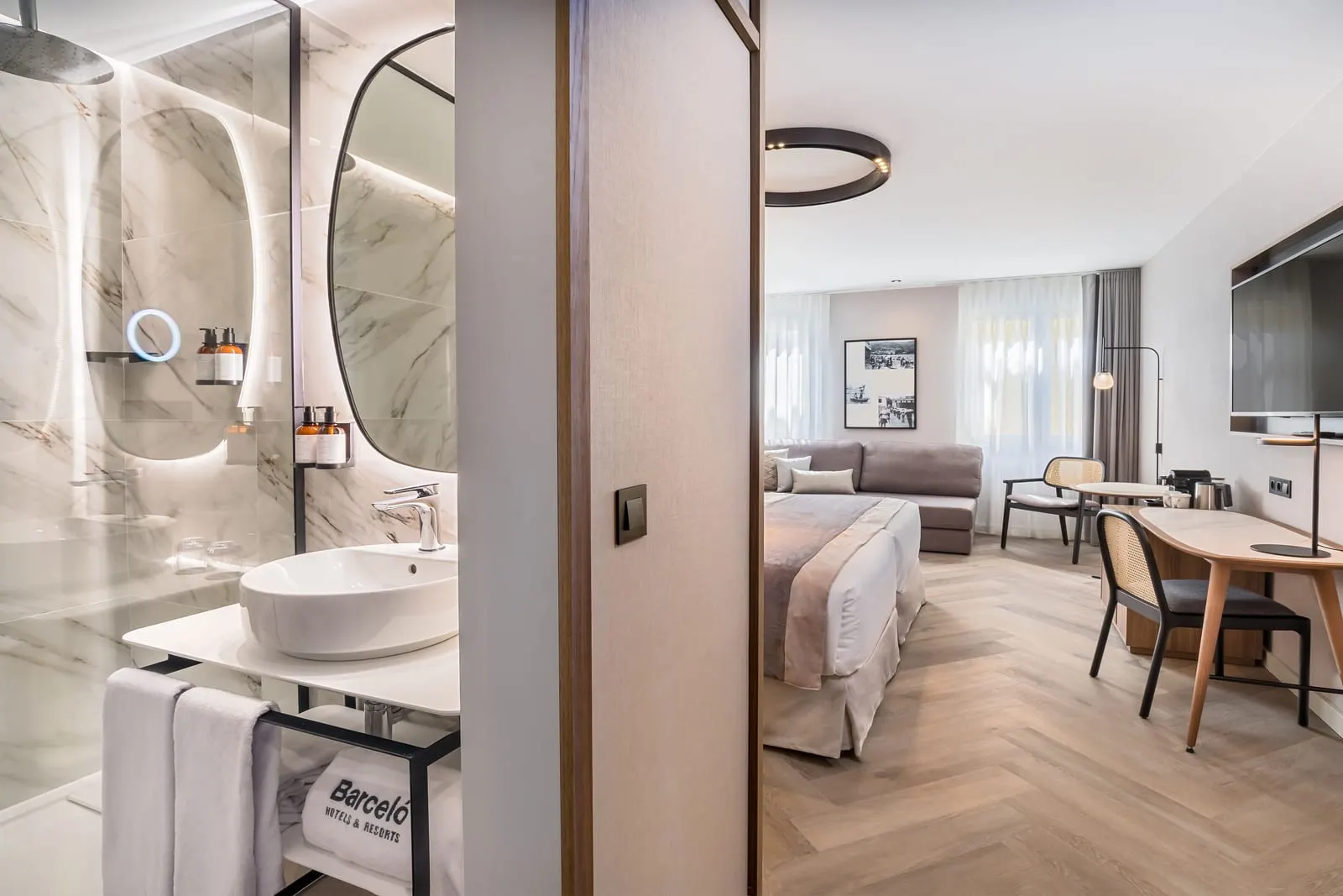 Junior Suite at Barceló Funchal Oldtown: a marble bathroom with a basin and walk-in shower opening onto the bedroom, sofa bed and desk