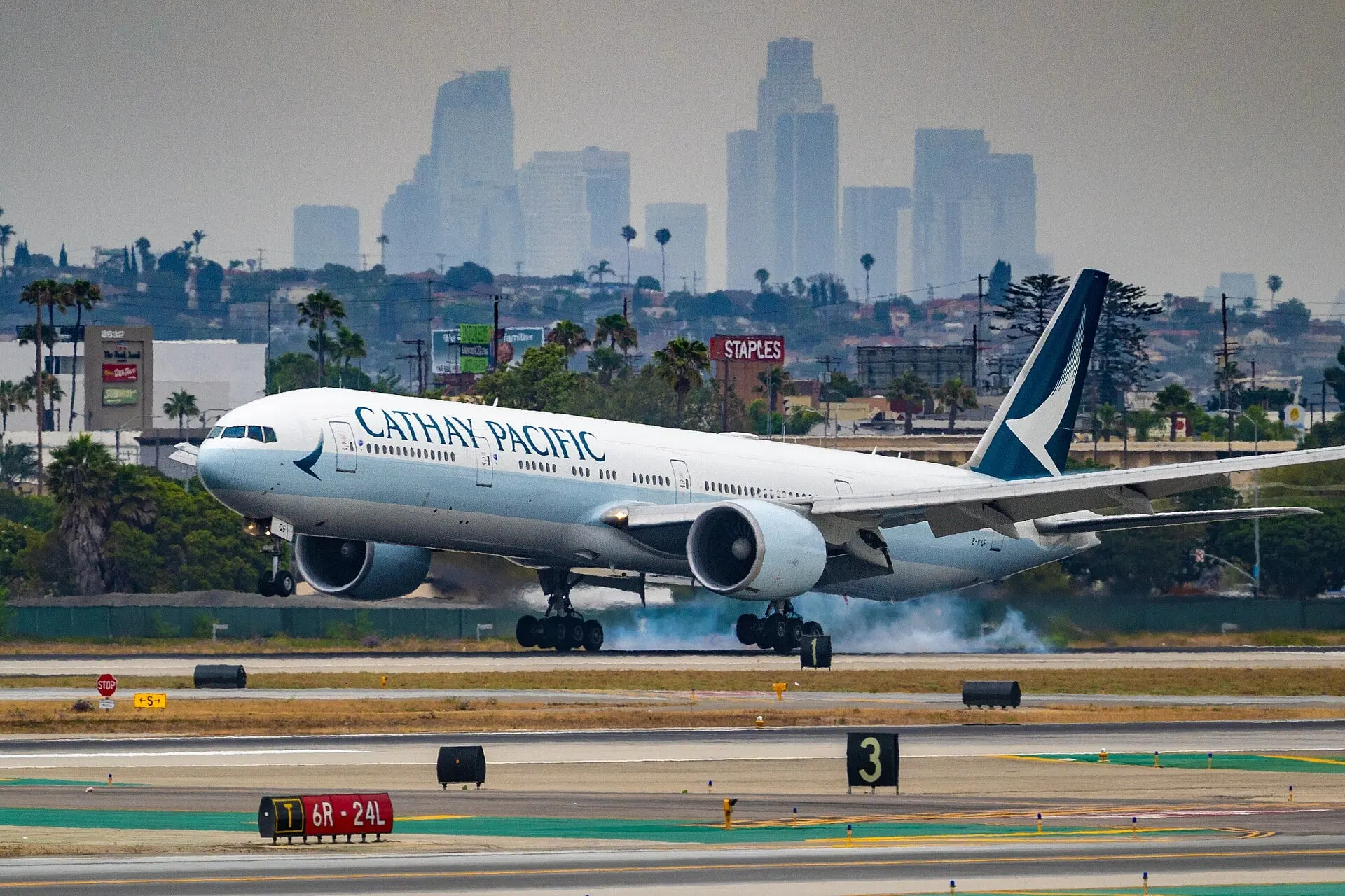 A Cathay Pacific Boeing 777 touching down at LAX, seen from the west gates