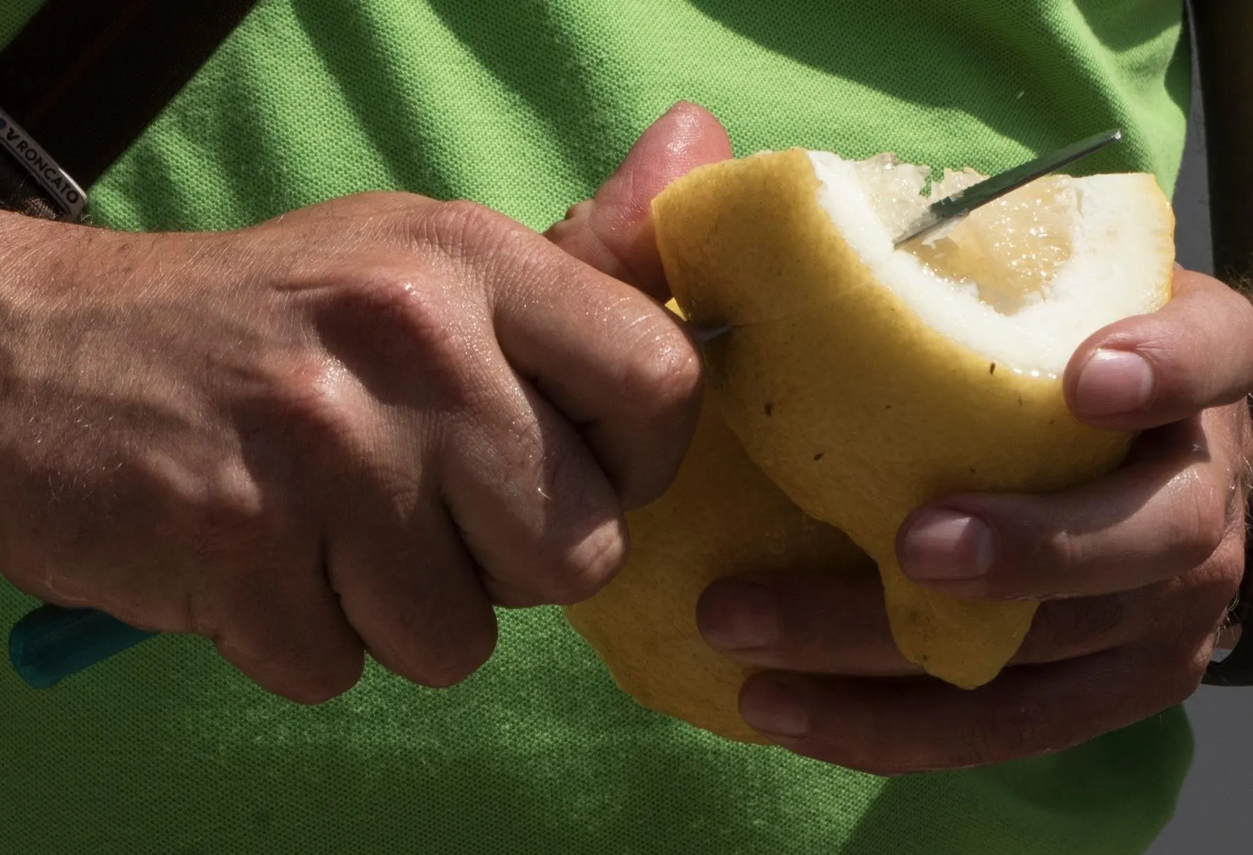 Hands cutting into a thick-skinned Amalfi lemon with a small knife