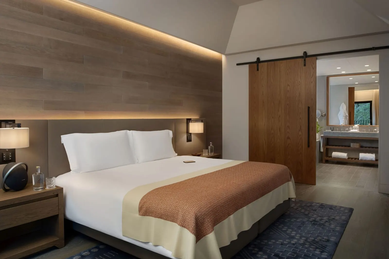 Valley Suite at Six Senses Douro Valley: the bed against a wood-panelled wall, with a sliding door to the bathroom