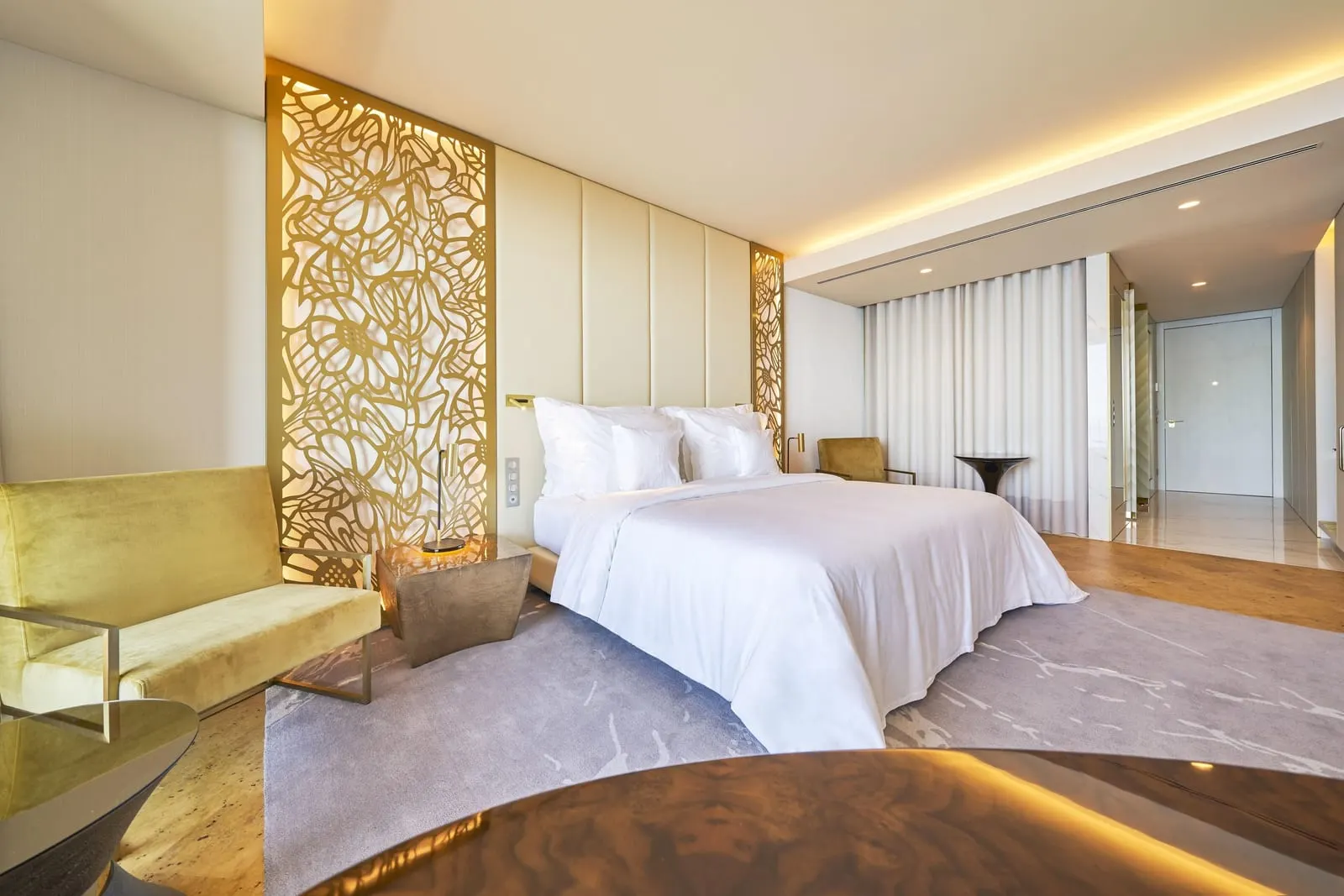Ocean Room im Savoy Palace: ein Kingsize-Bett vor einem gepolsterten Kopfteil mit goldenen Gitterpaneelen, ein Samtsessel und ein Holzboden mit grauem Teppich