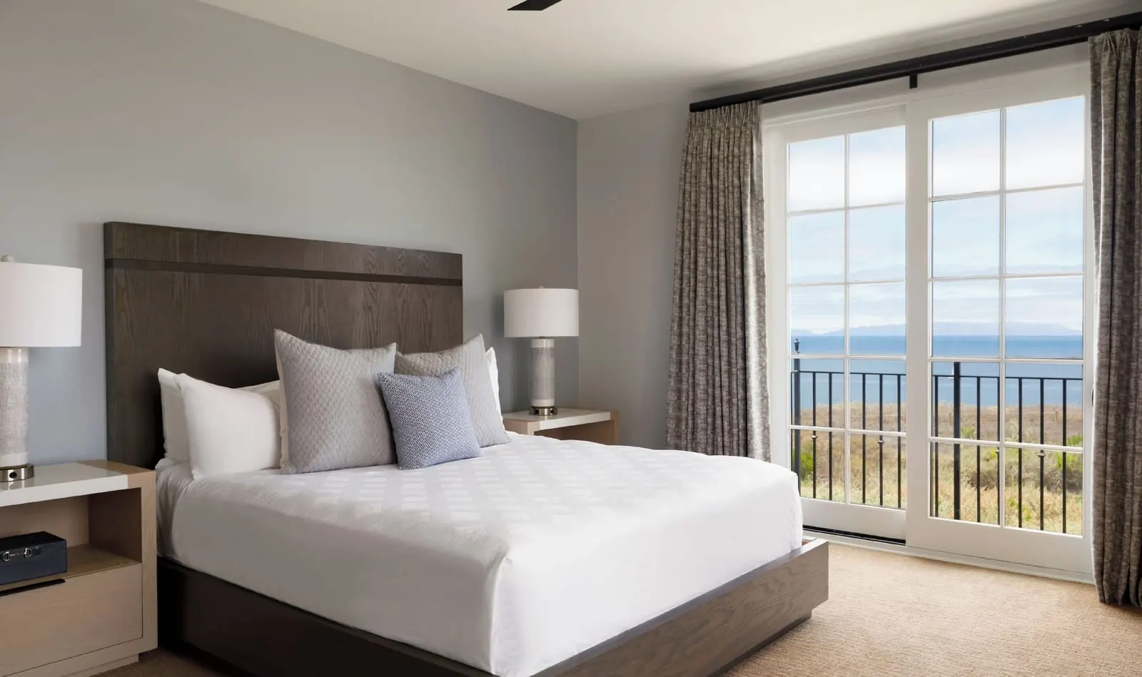 Casita King Guestroom, Ocean View at Terranea Resort: a king bed with a dark wooden headboard and glass doors onto a balcony with the sea beyond