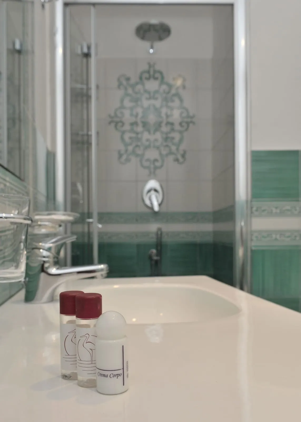 Superior Room at Hotel Santa Lucia: the bathroom, with a glass shower and green and white tiles behind a white basin