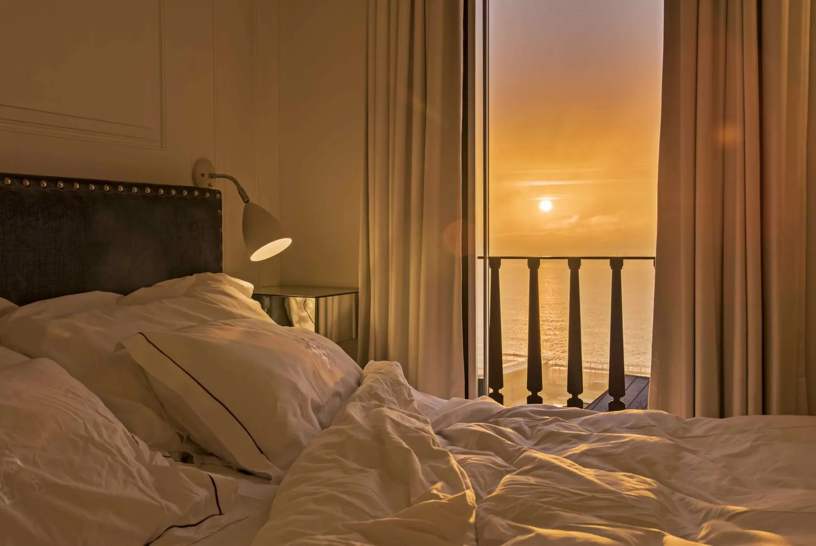 Classic River Bedroom at Santiago de Alfama: the bed and a window railing, with the sun low over the river