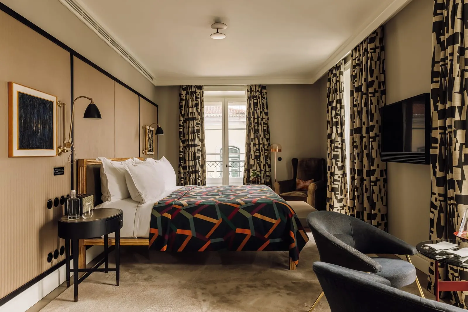 Alecrim Signature Suite at Bairro Alto Hotel: the bed with a geometric throw, patterned curtains and a French window beyond