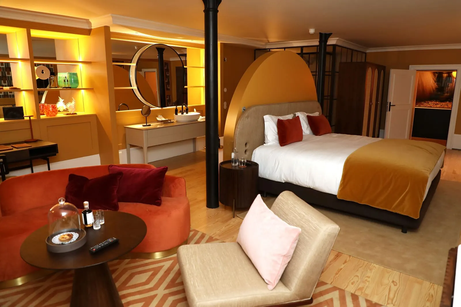 Lisboa Suite at Sublime Lisboa: a velvet sofa and a lounge chair in front of the bed and its tall arched headboard