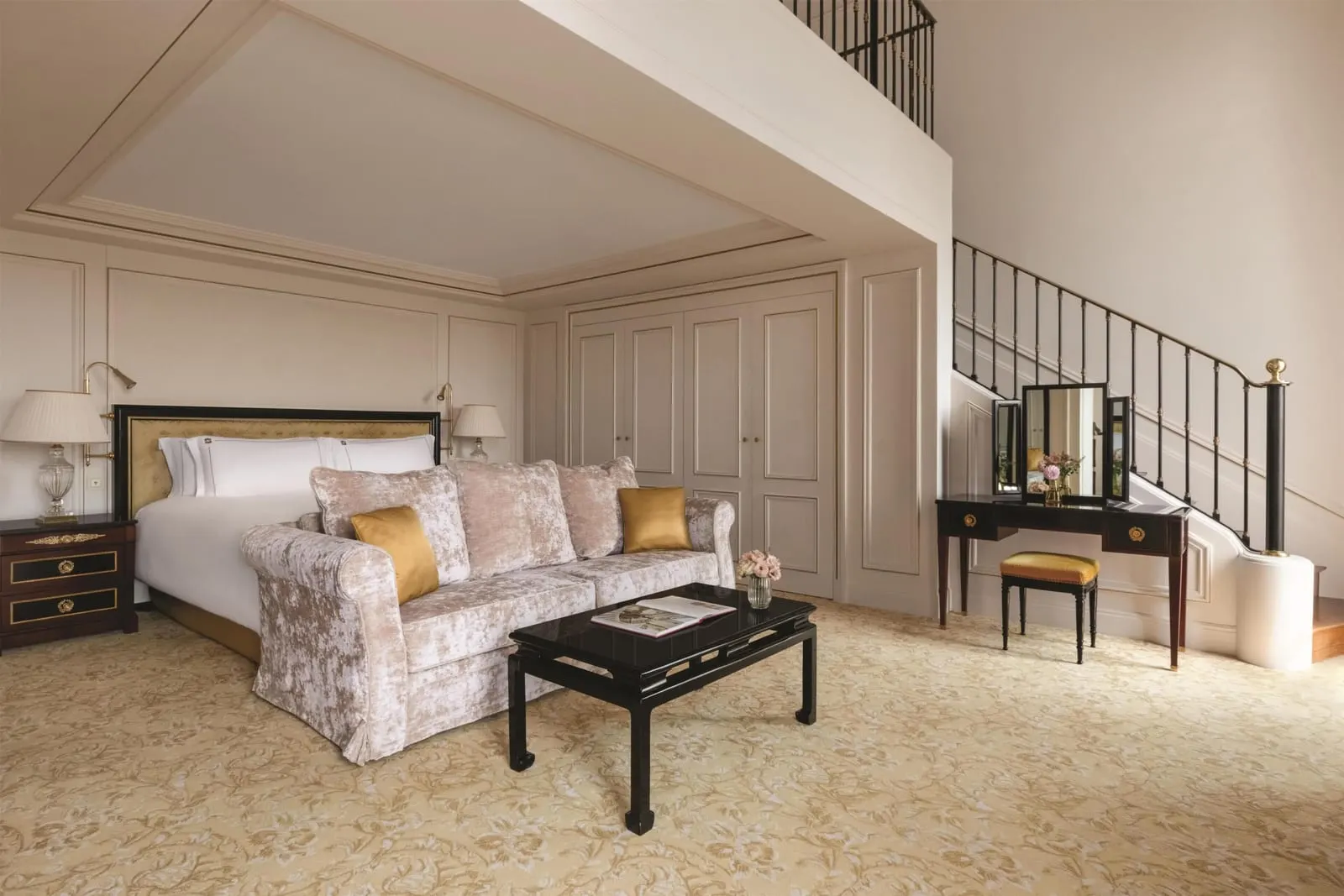 Duplex Eiffel View Suite at Shangri-La Paris: the lower level, with a king bed, a sofa, a dressing table and the staircase up to the mezzanine
