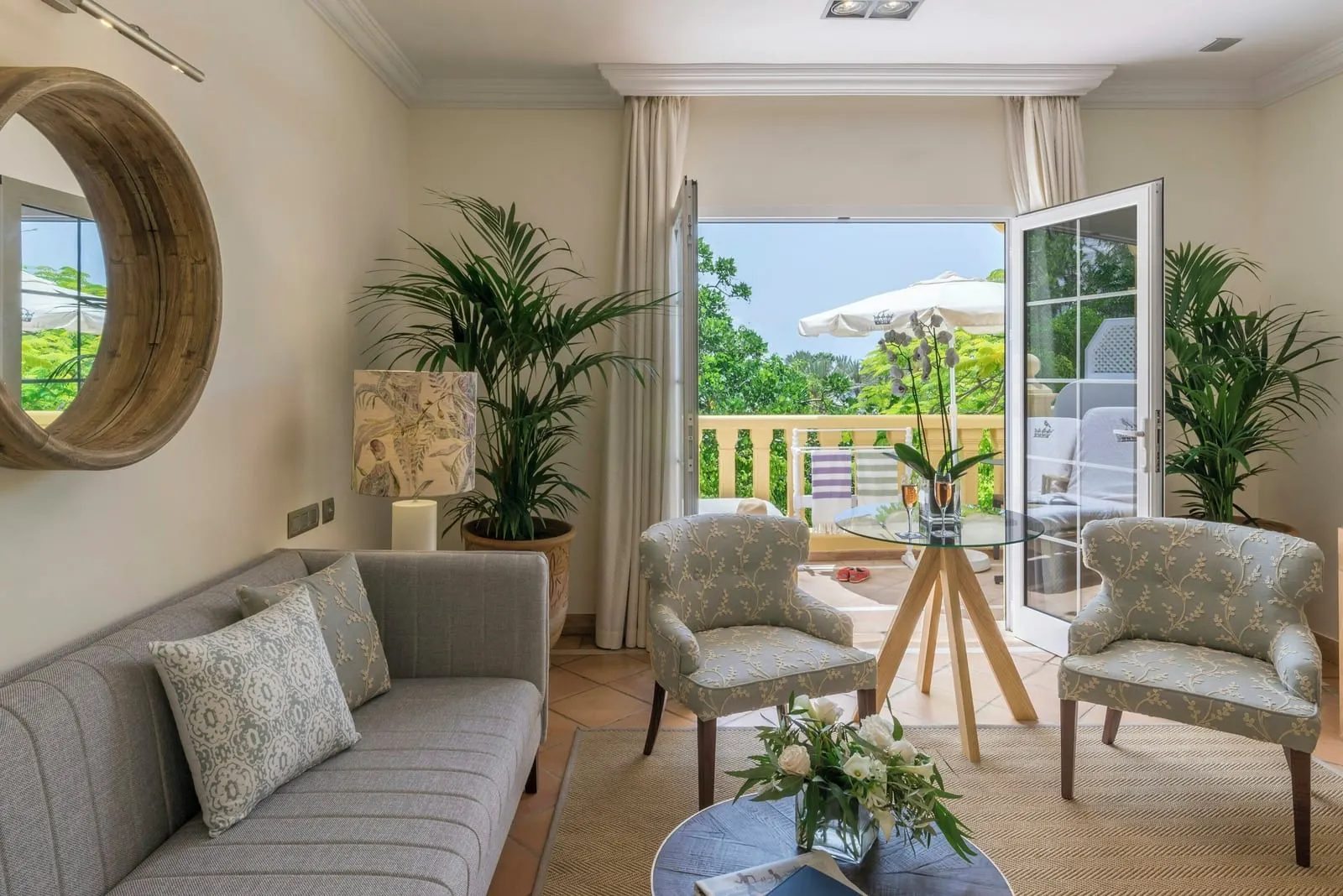 Casas Ducales Suite at Bahía del Duque: the living room, with a grey sofa, two armchairs and open doors to the terrace