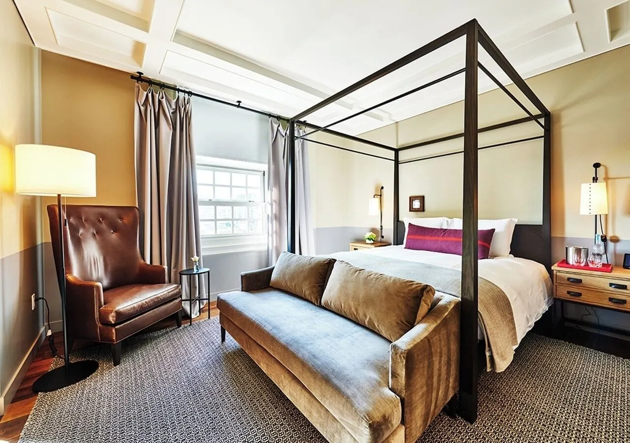 Roosevelt Suite im The Hollywood Roosevelt: ein Himmelbett mit einem Samtsofa am Fußende, ein Ledersessel und eine Stehlampe an einem Schiebefenster