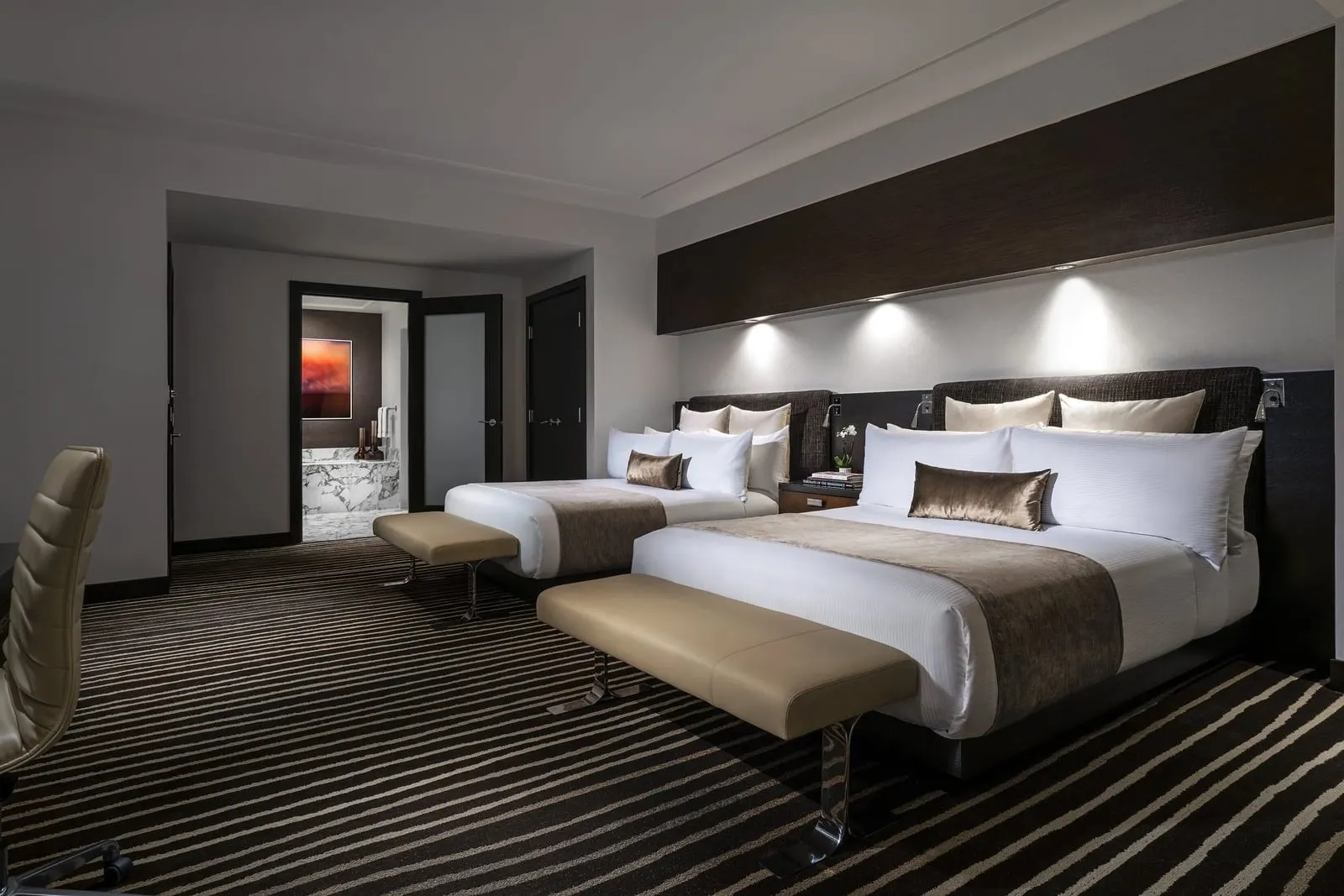 Canyon View 2 Queen Beds at Red Rock Casino Resort & Spa: two queen beds with an upholstered bench at the foot of each, and a door open to a marble bathroom