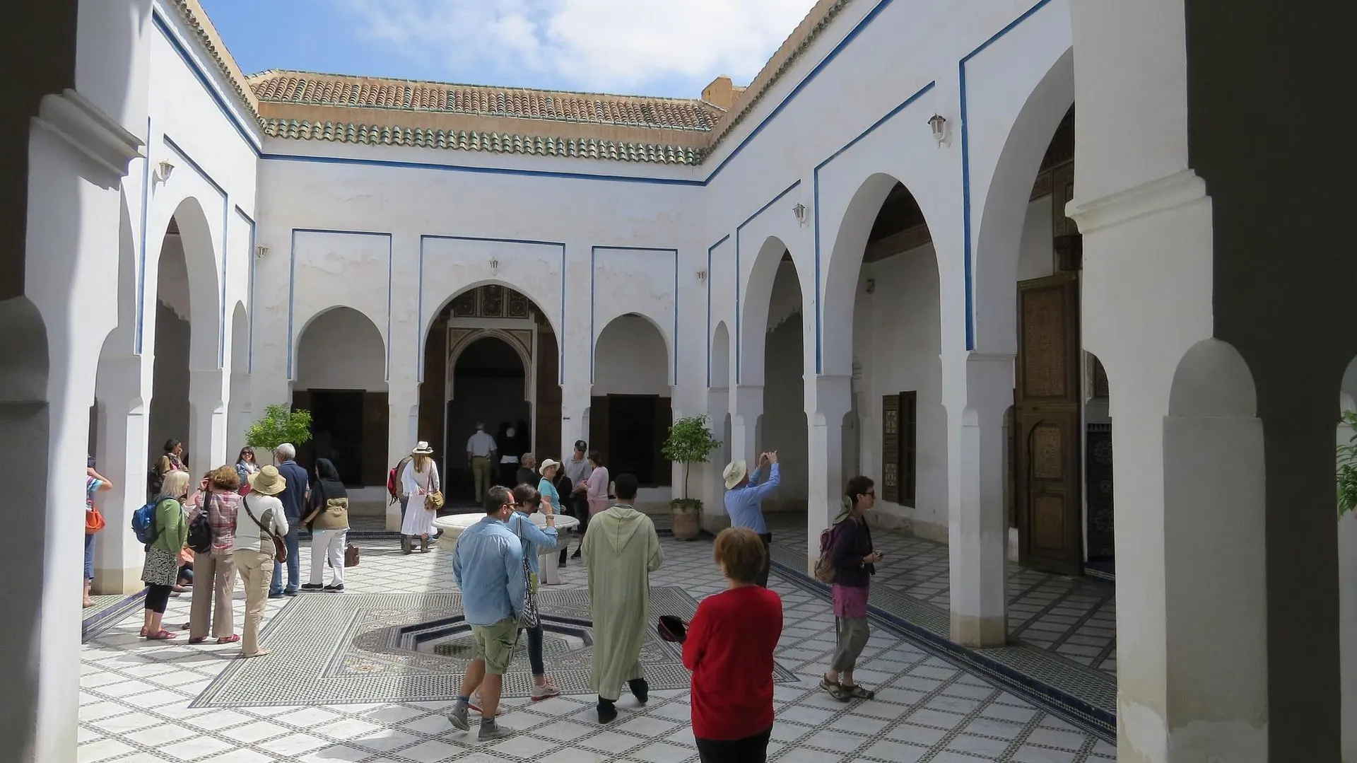 Visitors with a guide in a white arcaded courtyard of Bahia Palace