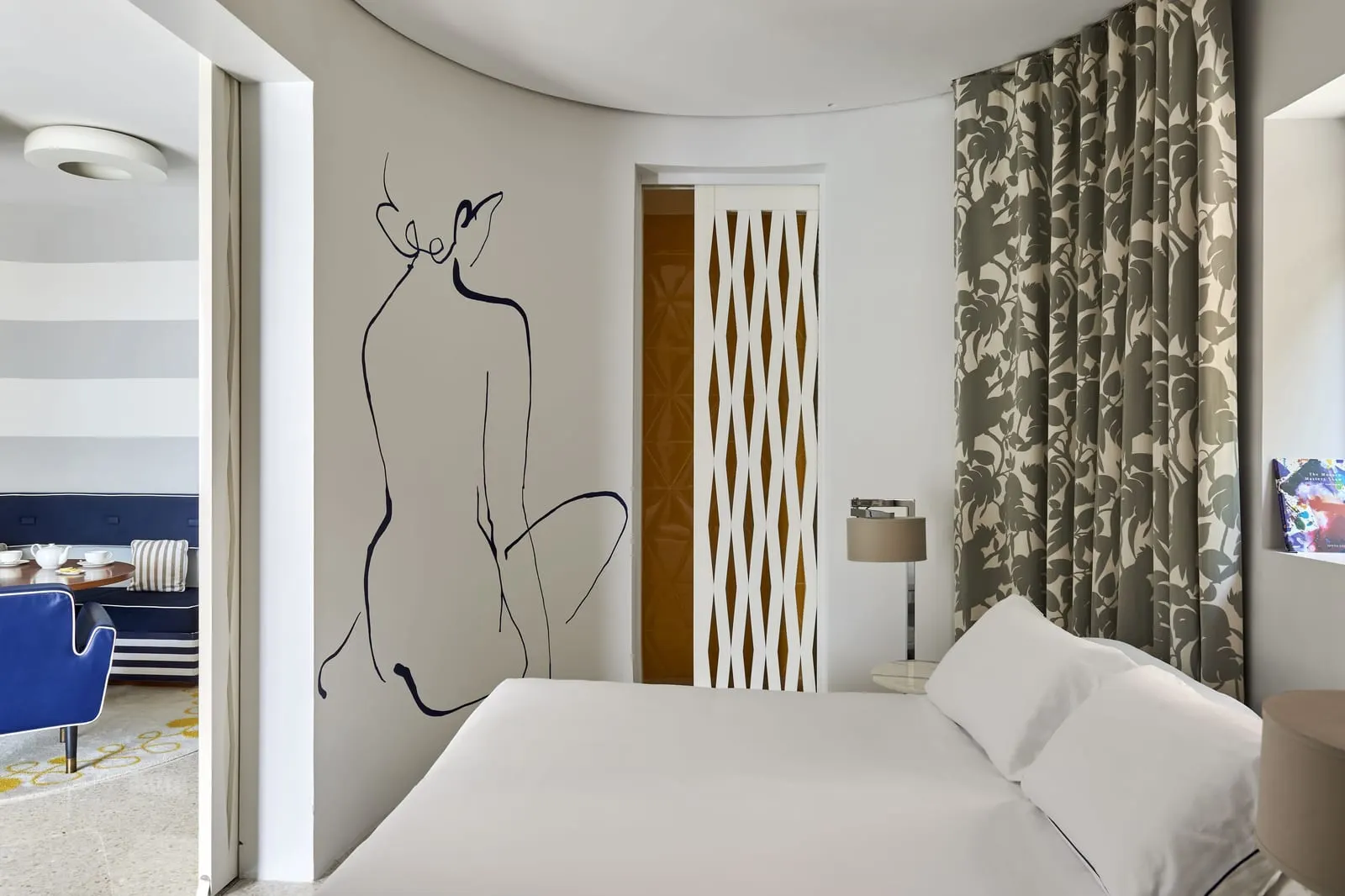 Exclusive Junior Suite at Monte-Carlo Beach: the bed below a line-drawn mural, with patterned curtains