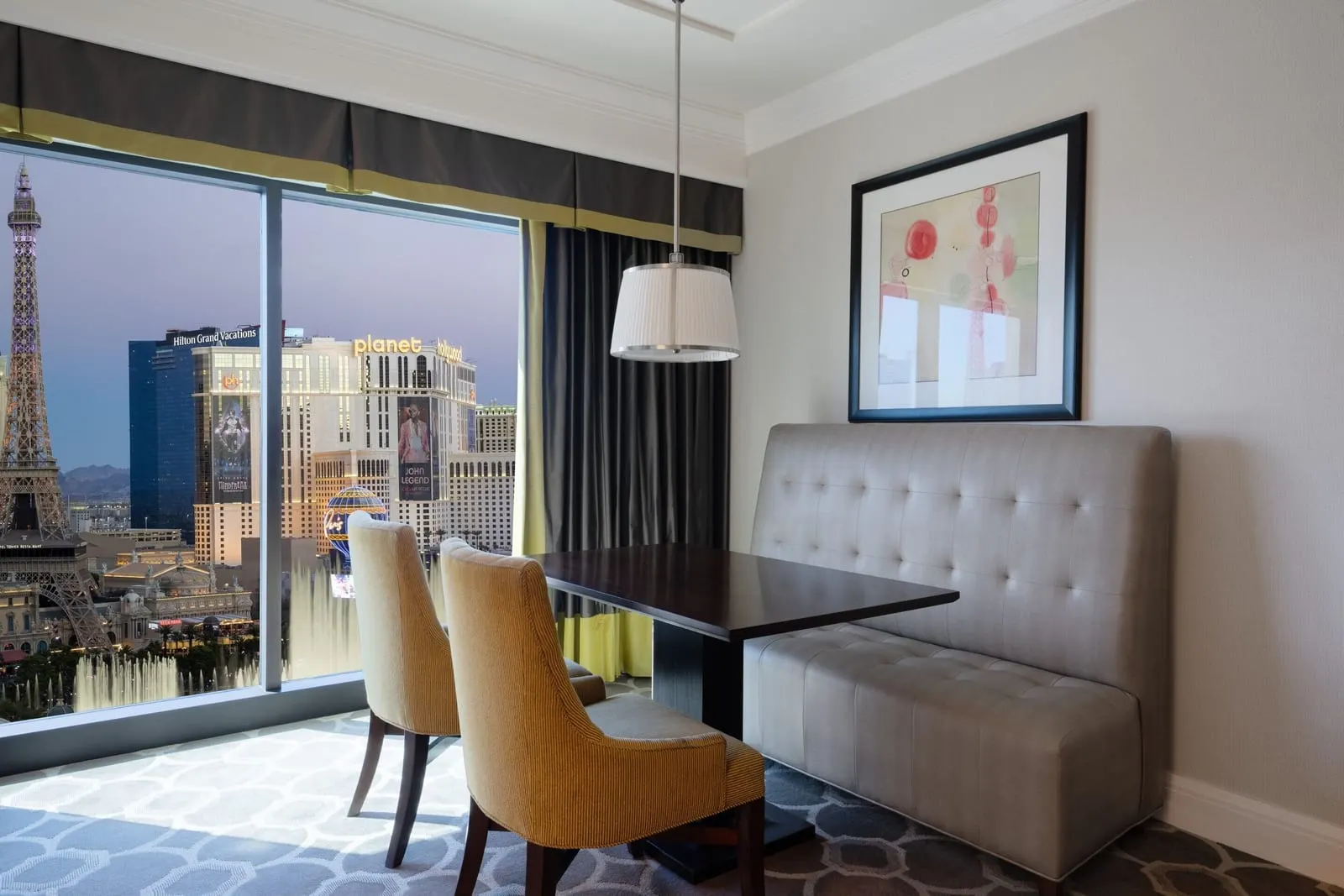 Octavius Executive Fountain View Suite im Caesars Palace: ein Esstisch mit Sitzbank und zwei Stühlen an einem raumhohen Fenster mit Blick auf den Strip und den Turm des Paris Las Vegas