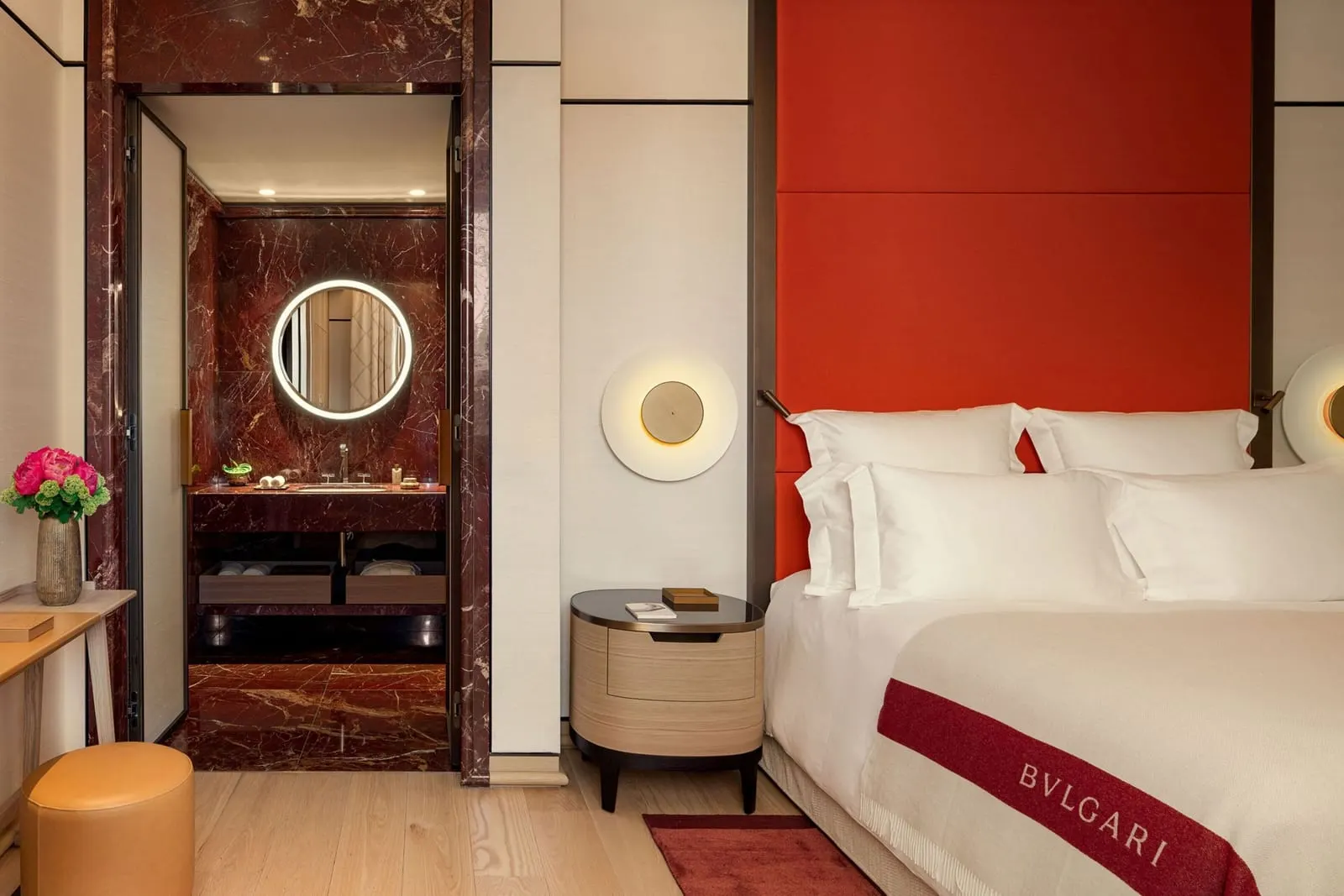 Deluxe Room at Bvlgari Hotel Roma: a bed with a red headboard, the red marble bathroom through the doorway