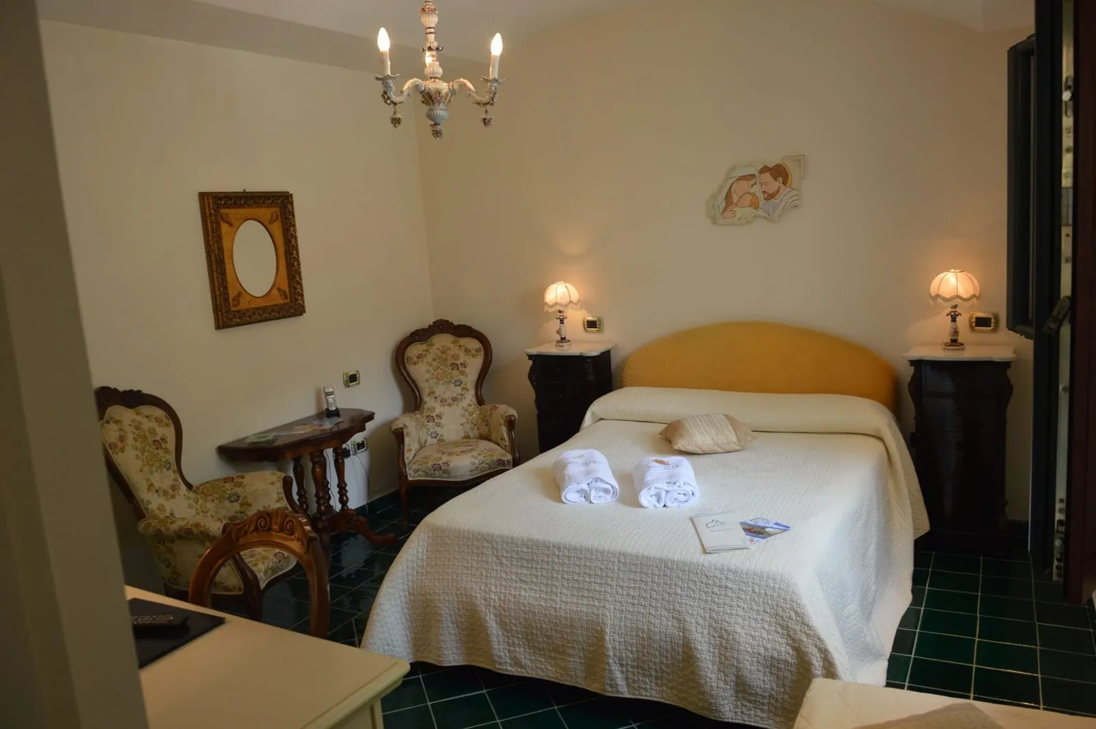 Luxury Outside at Hotel Santa Lucia: a double bed under a chandelier, with two upholstered antique armchairs and dark green floor tiles
