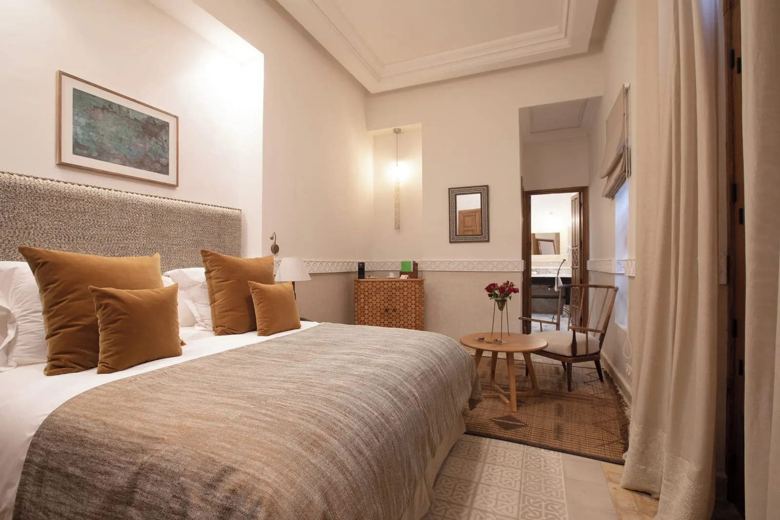 Family Suite at La Villa des Orangers: a double bed with an upholstered headboard and a small table with two chairs by the door.