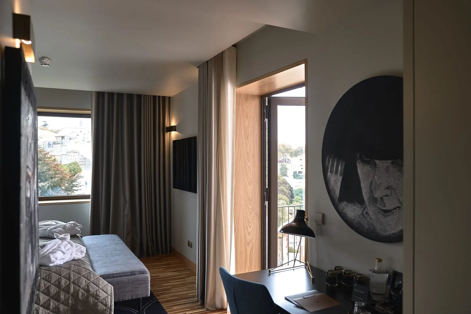 Executive Deluxe Room at Torel Avantgarde: a desk and lamp, a large round portrait and an open door to the balcony