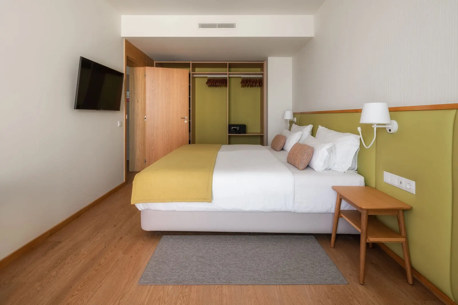 Suite Side Sea View at Sentido Galomar: a king bed with a yellow throw against a green headboard, a wall TV and an open wardrobe