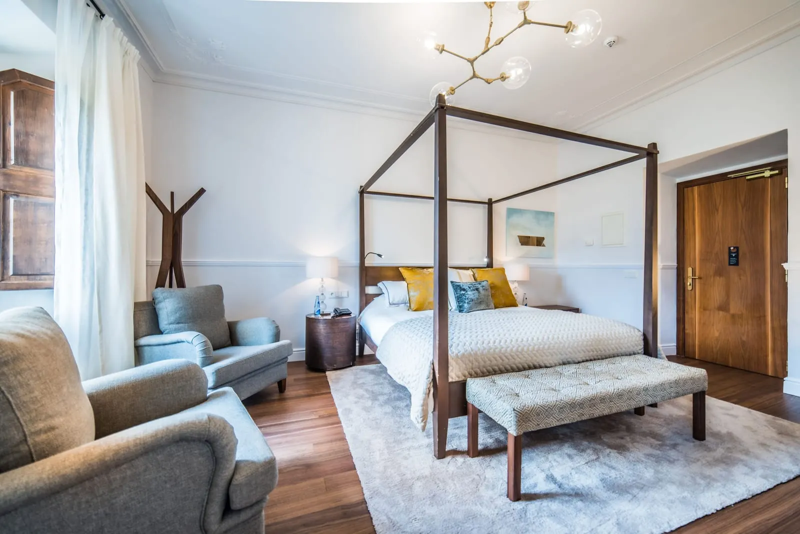 Double Room Superior at L'Avenida Hotel: a four-poster bed with a bench at its foot, two grey armchairs and a moulded cornice