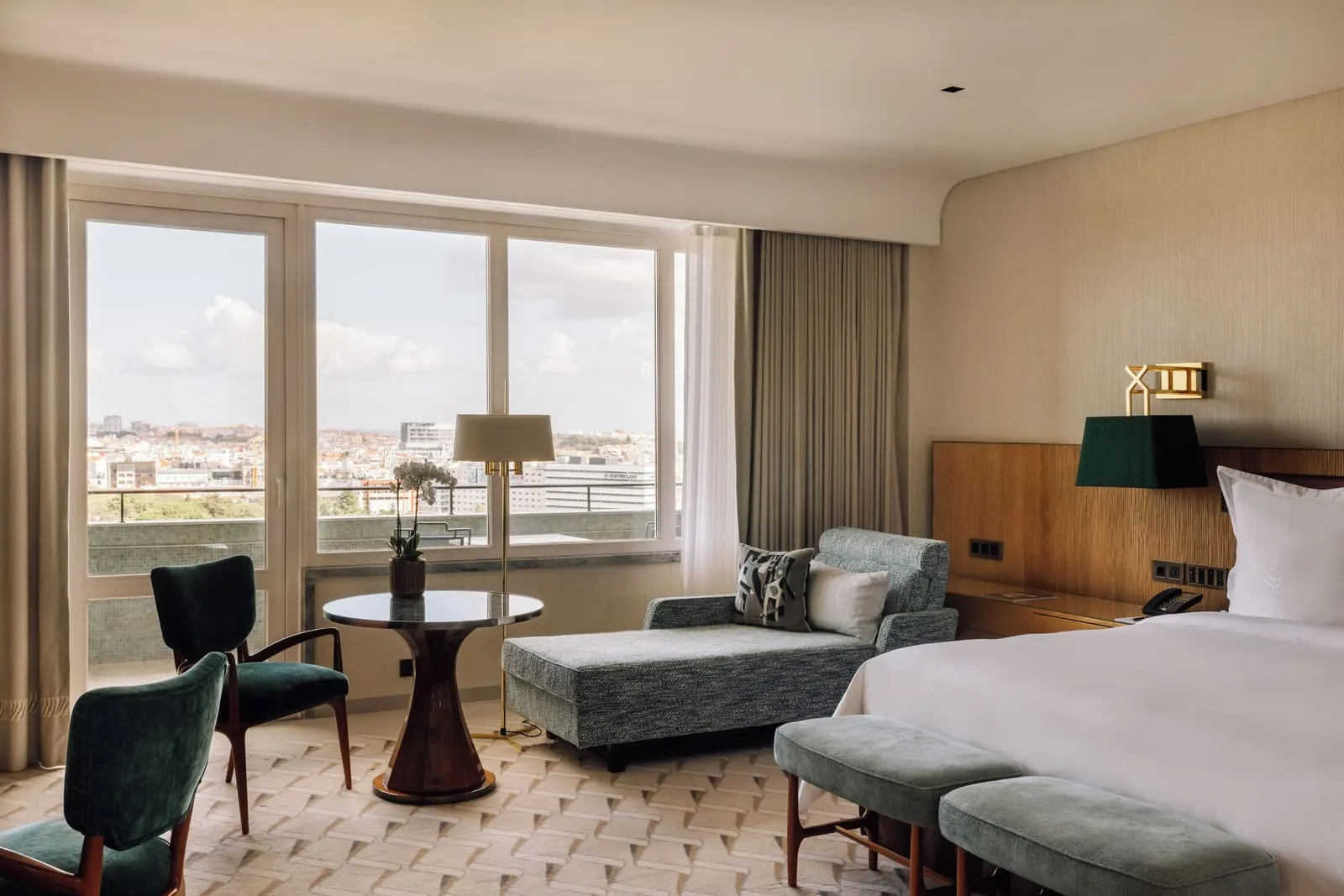 Panoramic View Room at Four Seasons Ritz Lisbon: a round table, green chairs and a daybed by wide windows over the city
