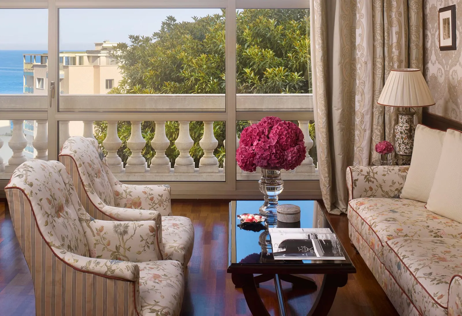 Azur Suite at Hôtel Métropole Monte-Carlo: armchairs and a sofa by a window, with a balustrade and trees outside