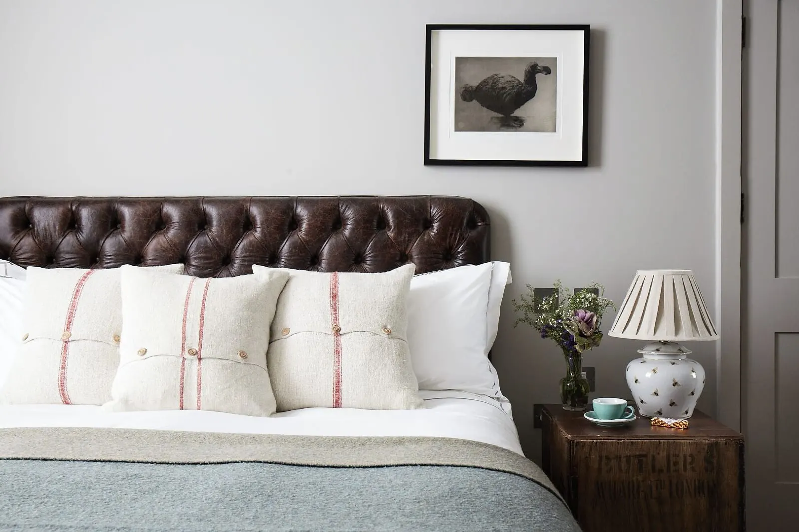 Medium Room at Artist Residence London: the bed with a buttoned leather headboard, a bedside lamp and a framed print