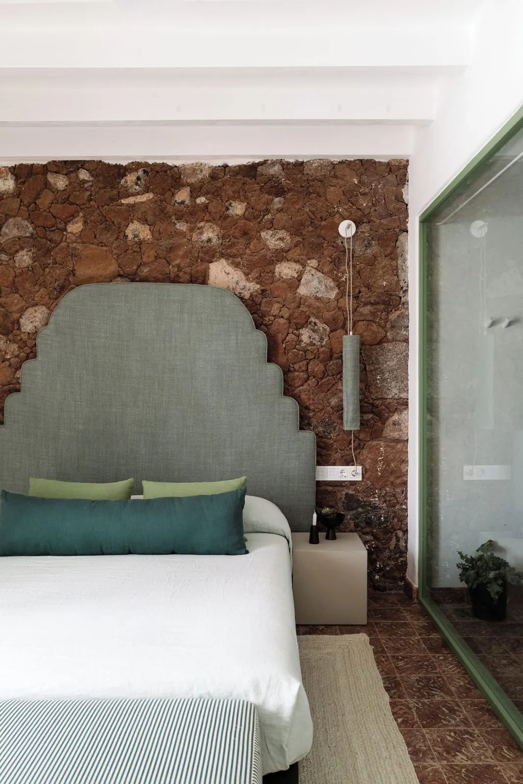 Superior Room with Terrace and Sea View à l'Hotel César Lanzarote : une tête de lit verte festonnée contre un mur en pierre volcanique