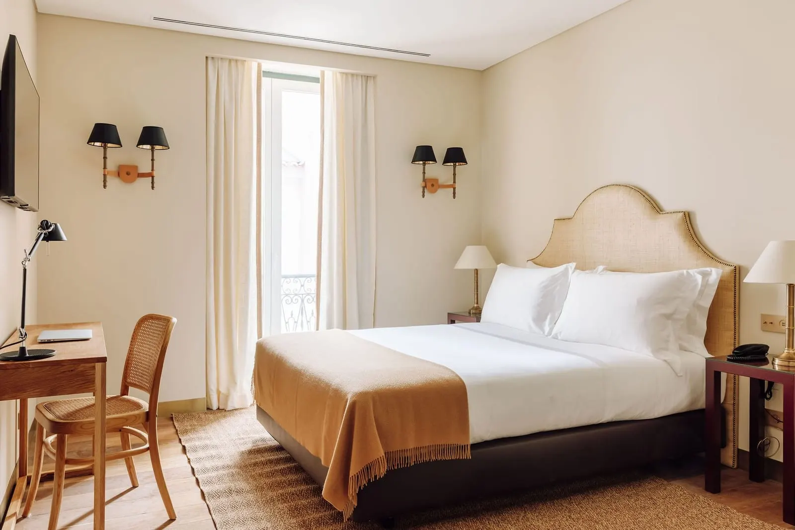 Deluxe Courtyard room at Hotel das Amoreiras: the bed, a desk and cane chair, and a glass door to a small iron balcony
