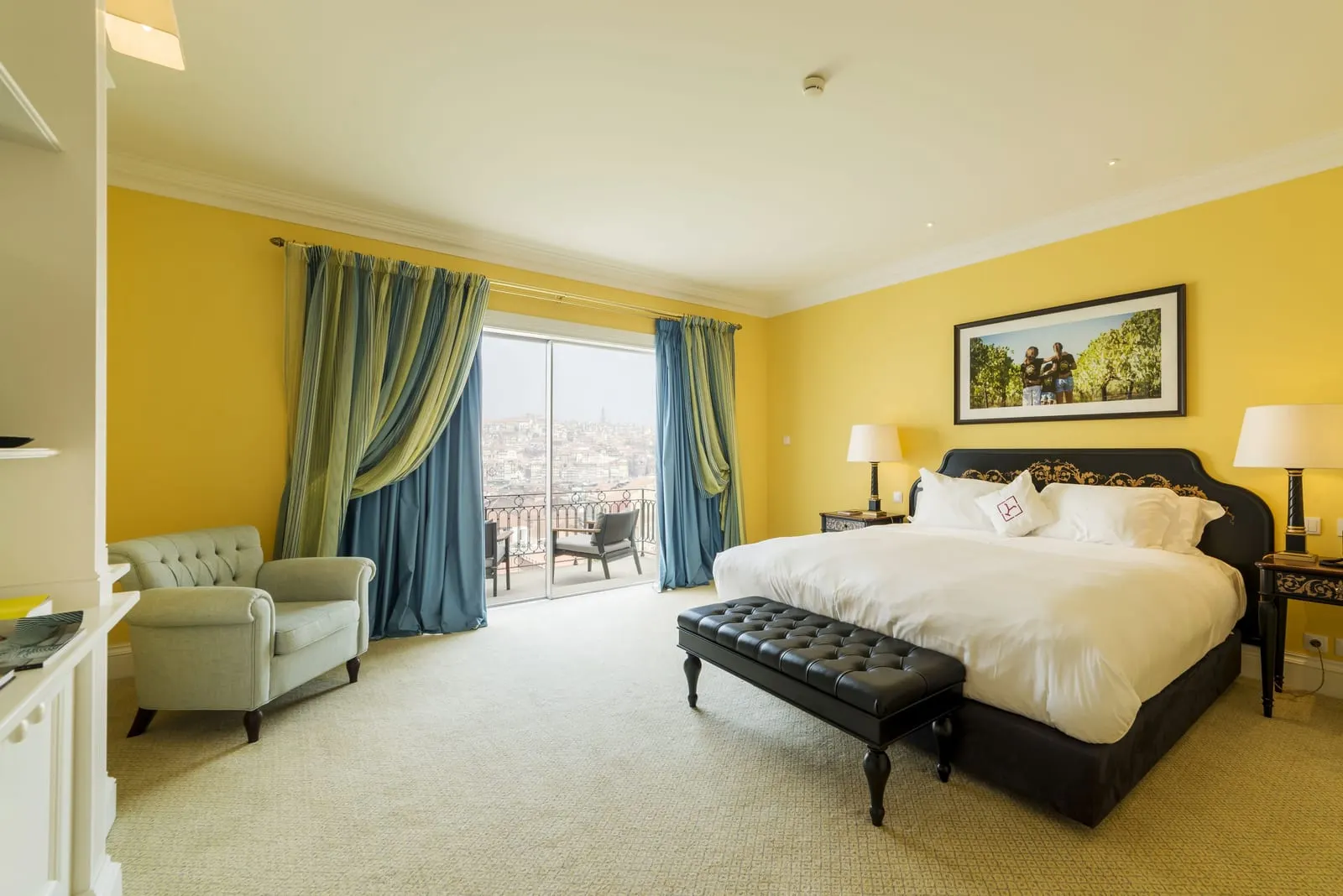 Executive Room at The Yeatman: the bed with a leather bench, an armchair and glass doors to a terrace with two chairs