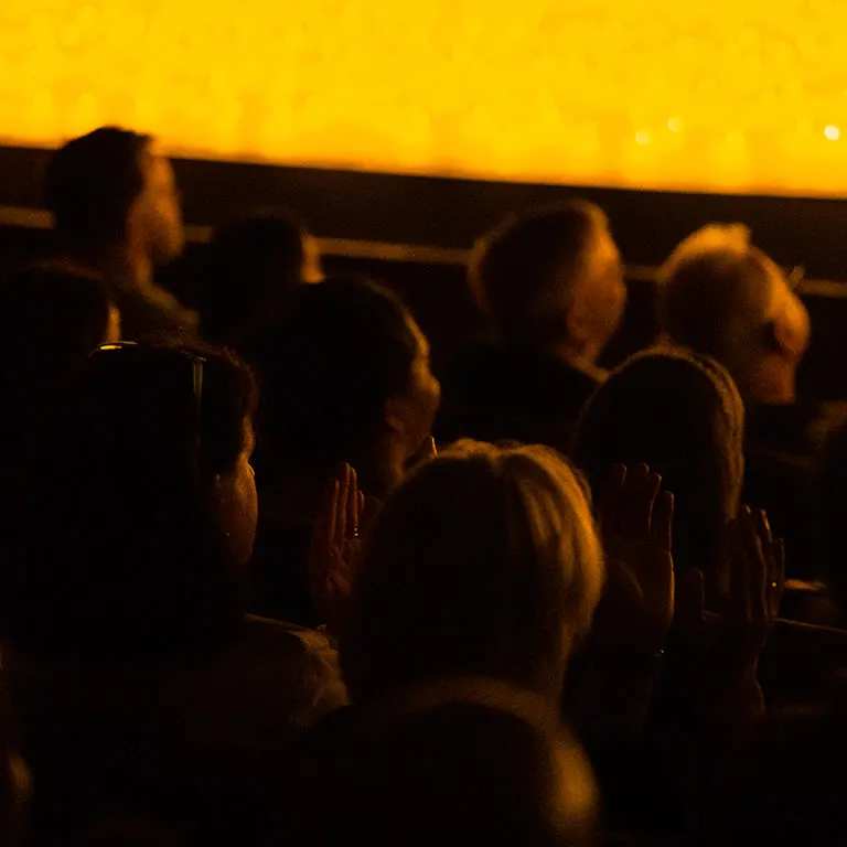 Audience members watching a Candlelight concert beneath a ledge lined with glowing candles