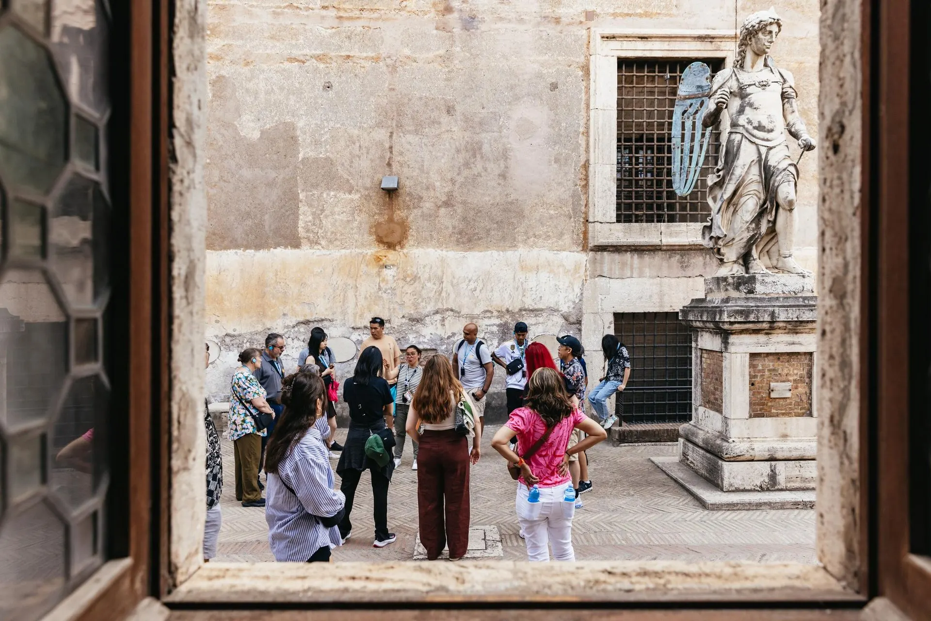A group in a courtyard of Castel Sant'Angelo, seen through a window