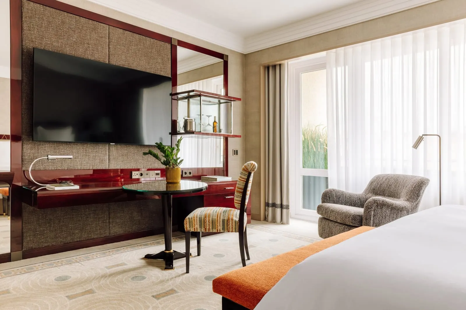 Deluxe Room at Four Seasons Ritz Lisbon: a desk below the TV, a round table, an armchair and a glass door to the terrace