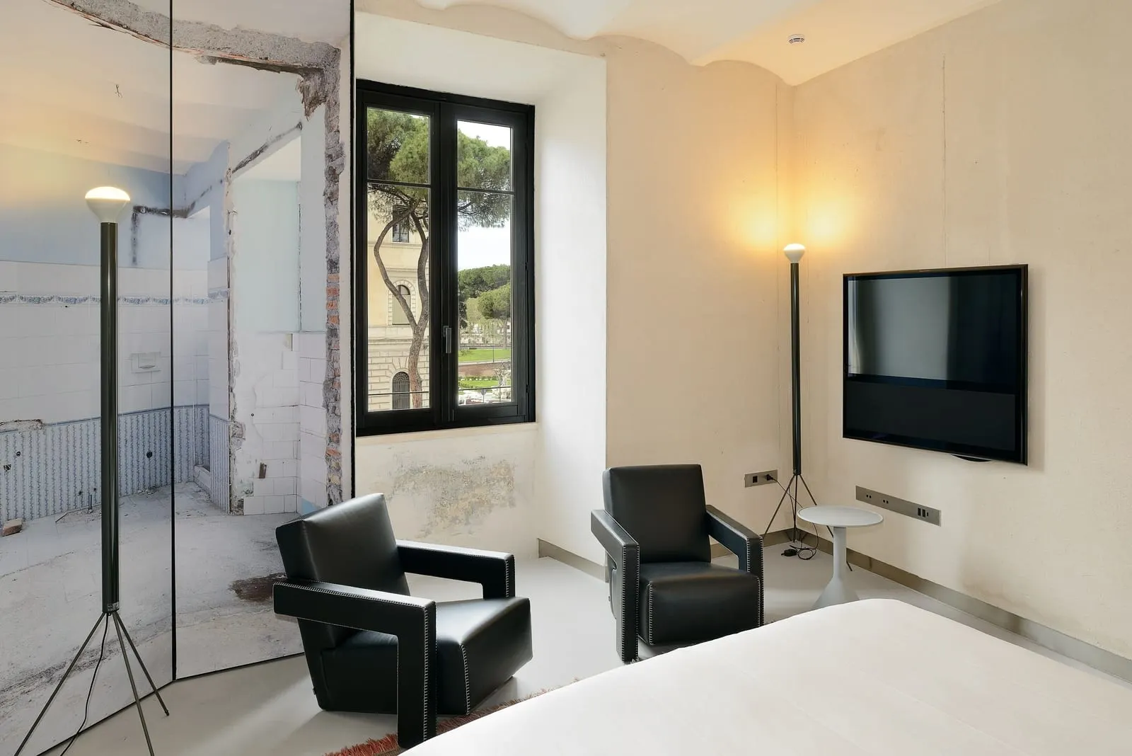 Superior Apartment at Rhinoceros Roma: two black armchairs, a wall TV and a window onto trees, the bed in the foreground