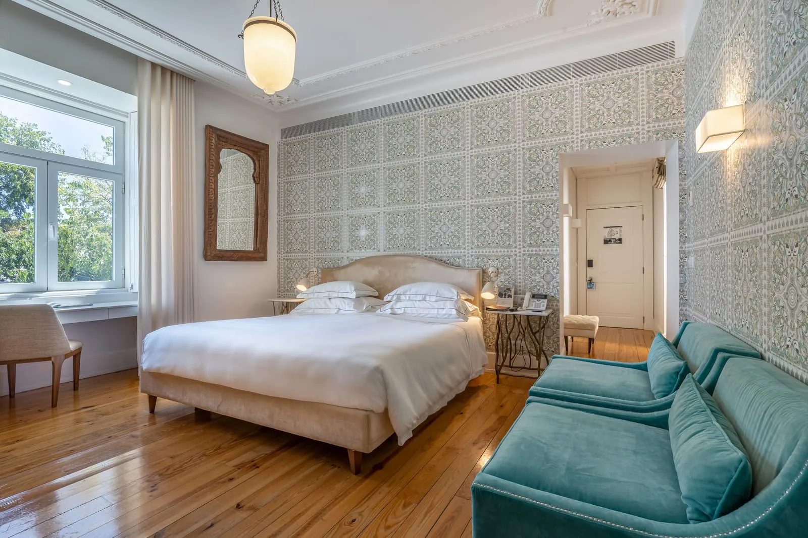 Deluxe King Bedroom at Santiago de Alfama: the bed, patterned walls, a teal sofa and a tall window
